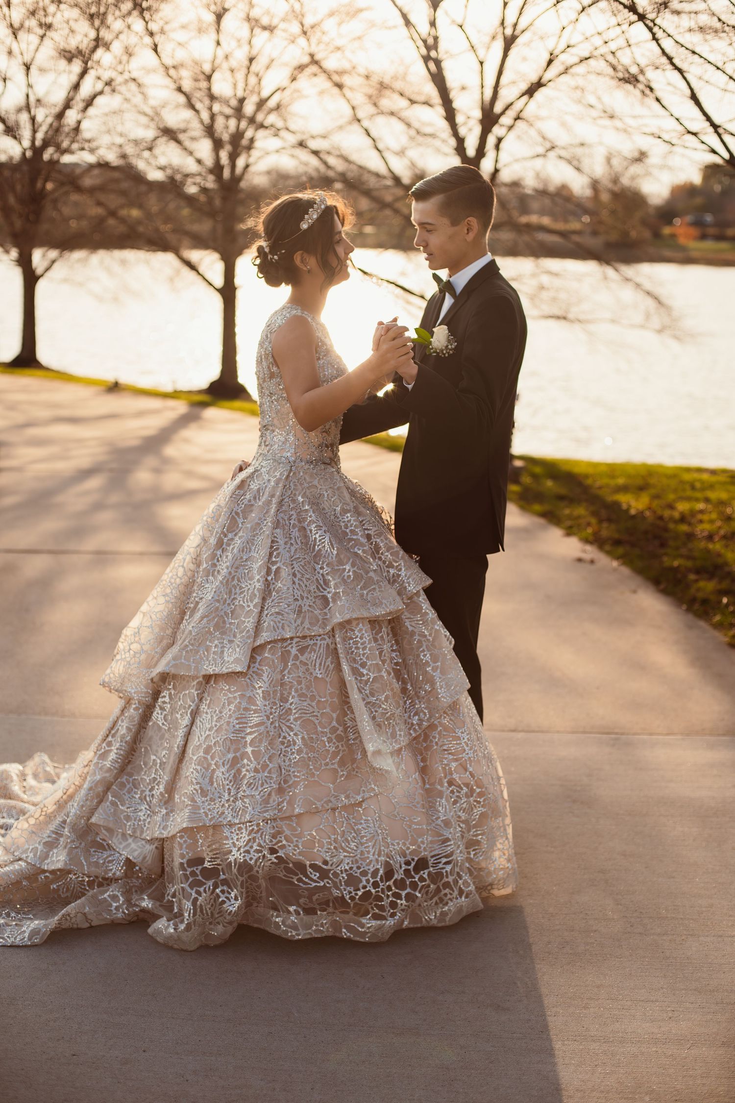 Romantic sunset portrait of couple in formal wear on pathway by lake.