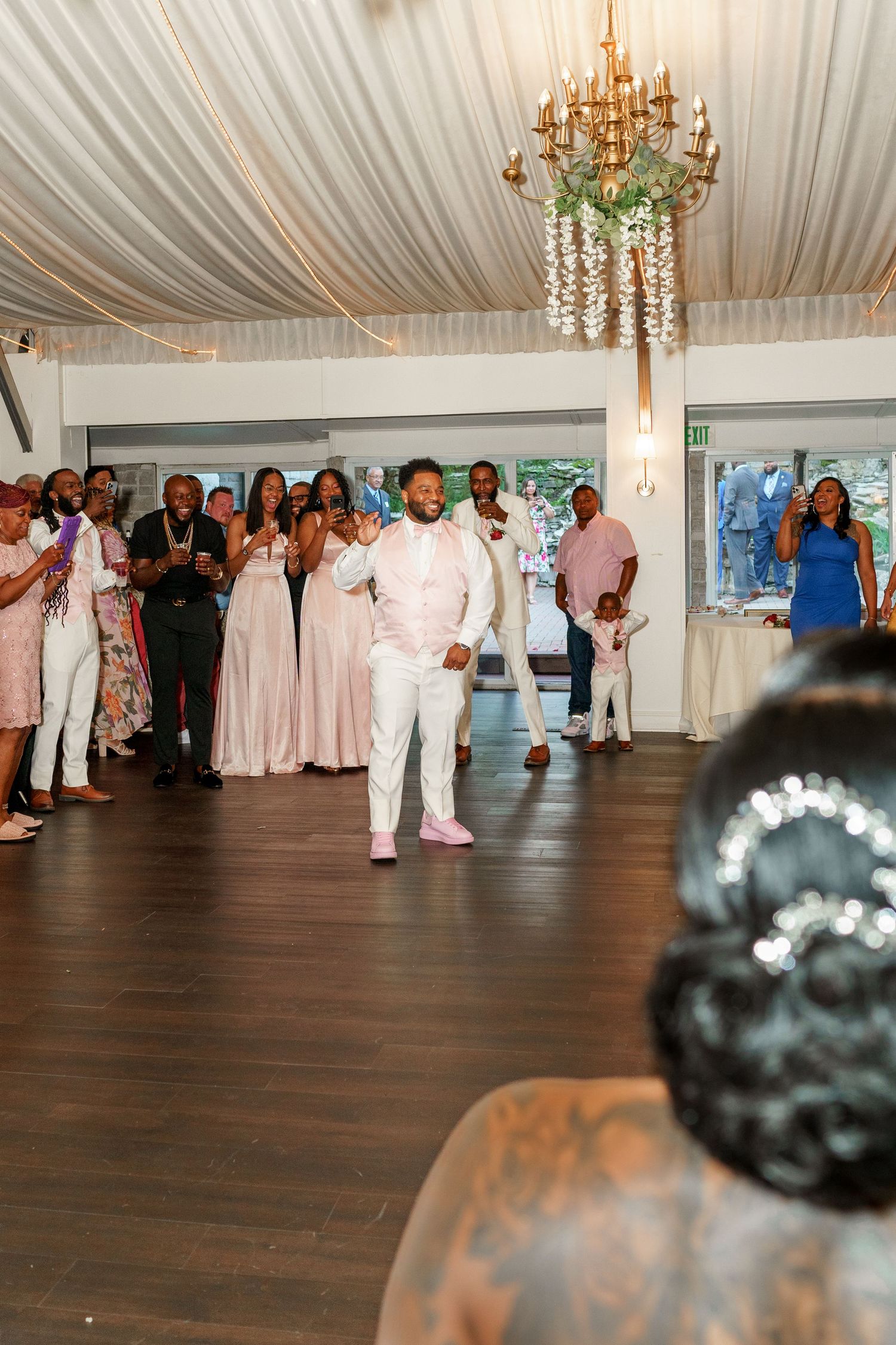 Wedding party and guests lined up at reception venue with elegant decor and lighting.
