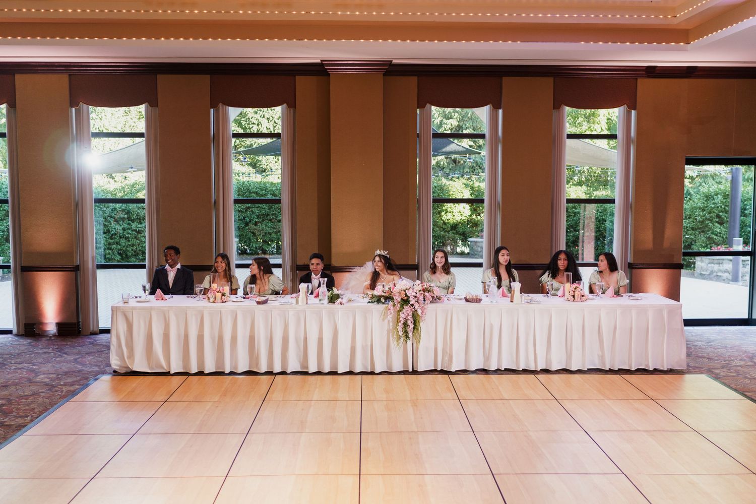 Empty dance floor and reception tables arranged in a spacious banquet hall with natural lighting from windows.