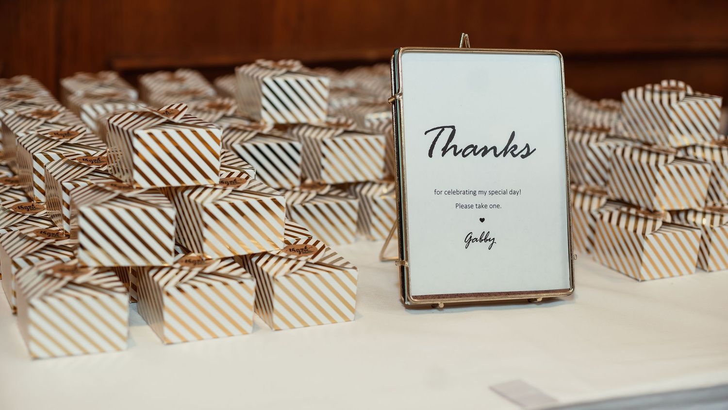 Striped favor boxes arranged neatly with a 'Thanks' sign at a wedding reception.