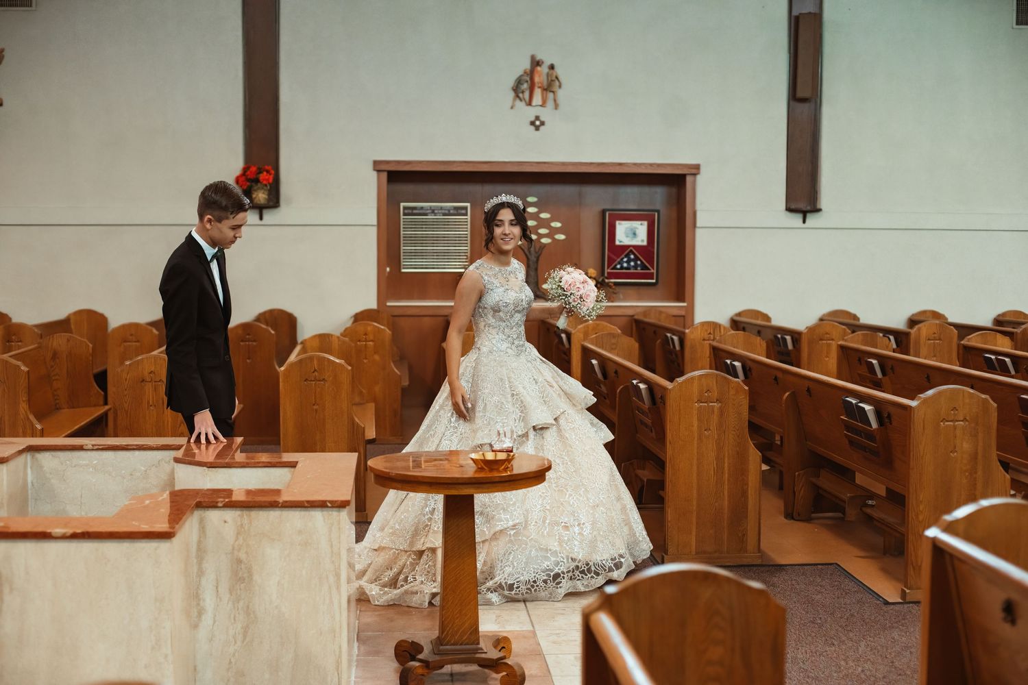 An elegant wedding gown with lace detailing in a traditional church setting with wooden pews.