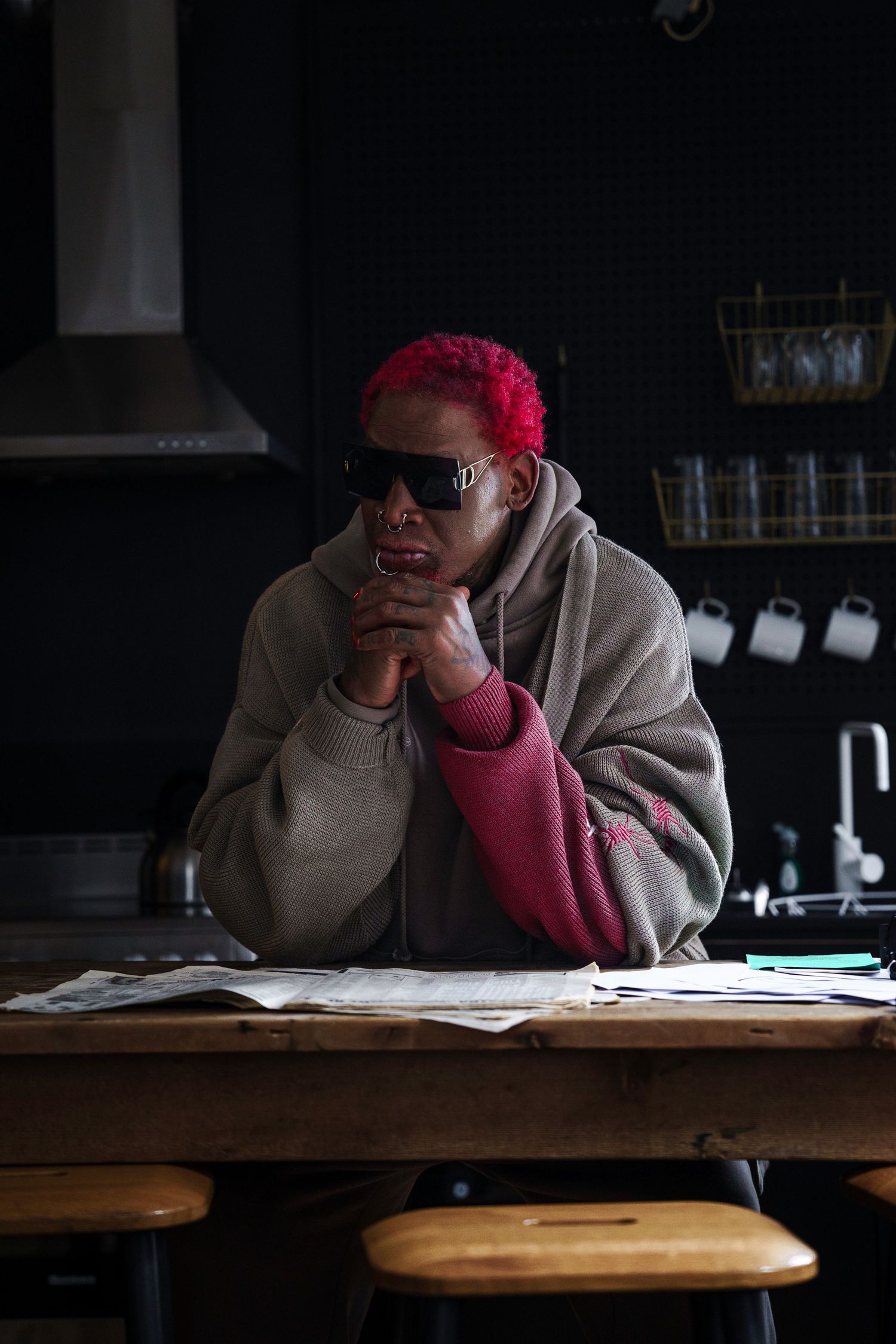 Person studying at desk in dimly lit room wearing red cap.