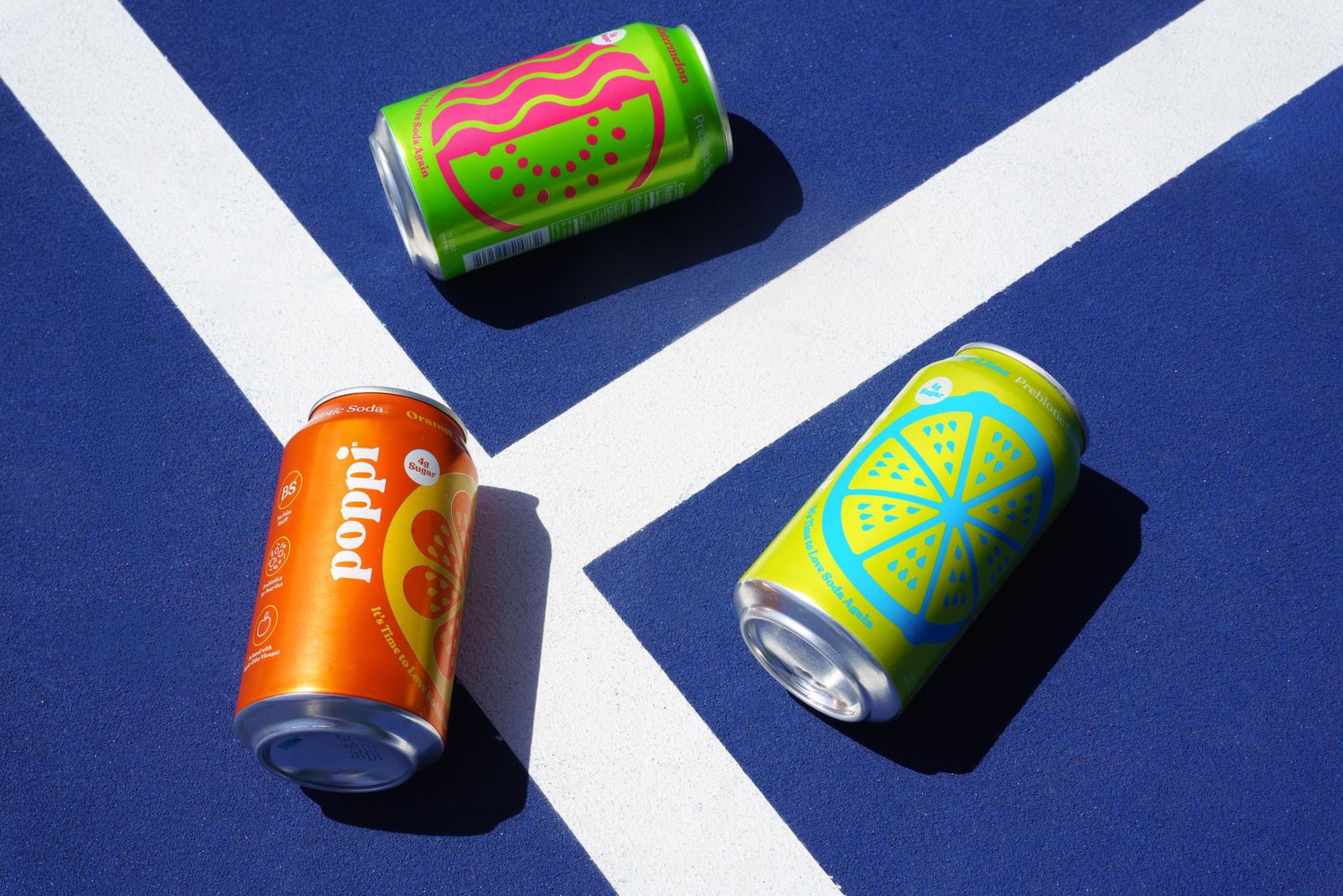 Colorful soda cans arranged in geometric pattern on blue background with white lines.