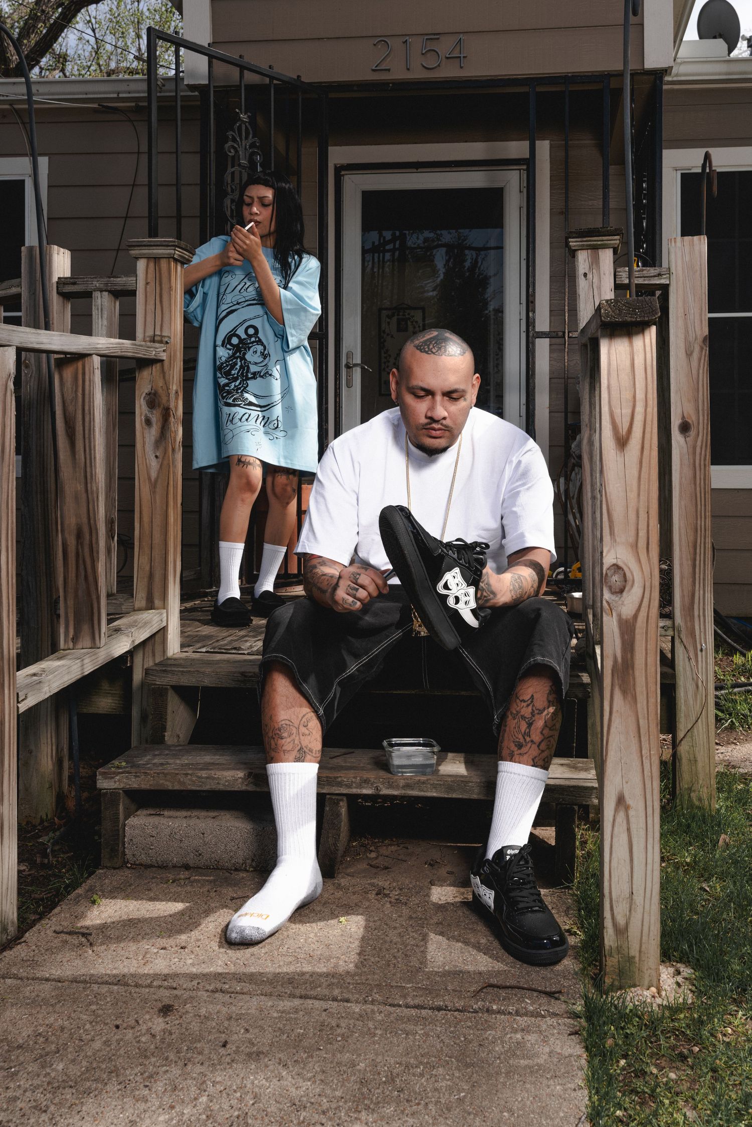 People sitting on wooden porch steps in white clothing.