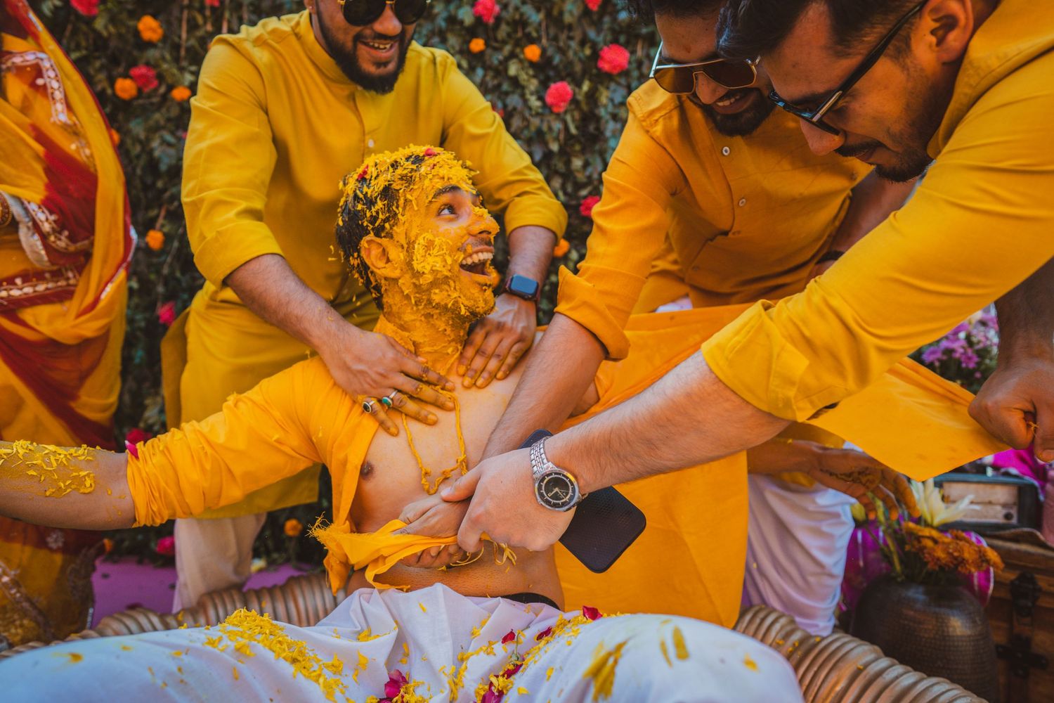 Group wearing yellow outfits participating in traditional Haldi ceremony.