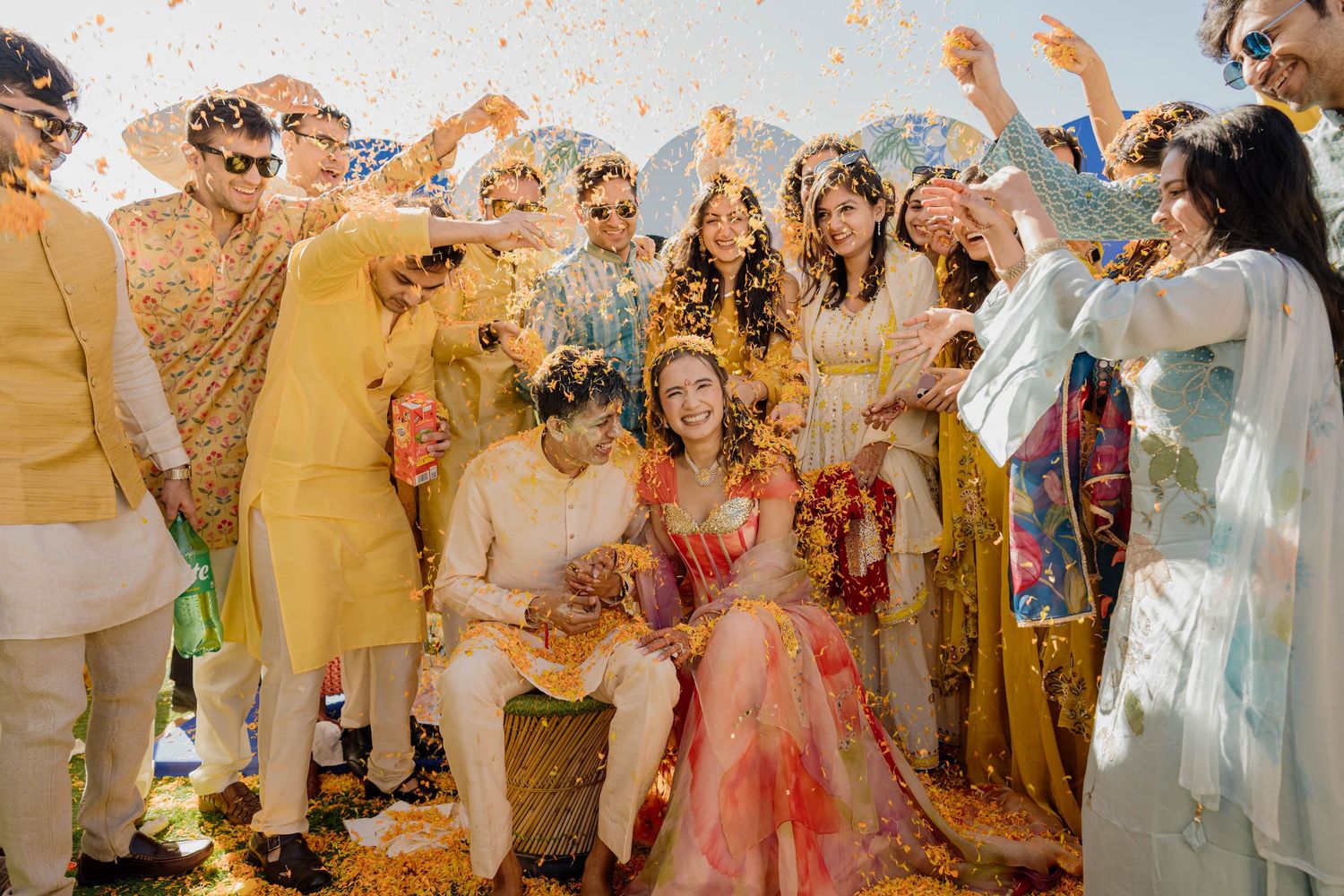 Joyful wedding celebration with guests dancing and throwing colorful confetti.