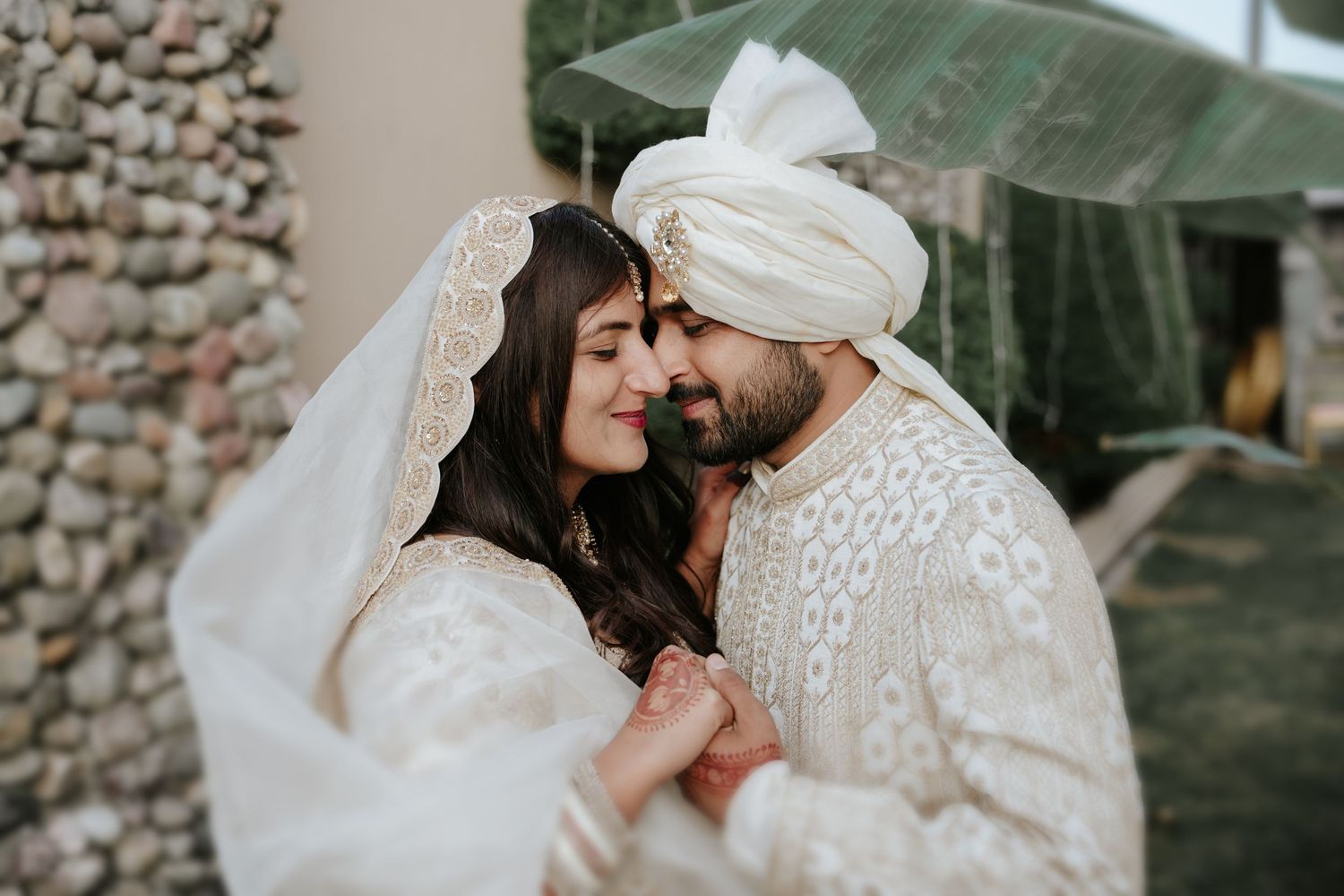Romantic outdoor wedding photoshoot with couple in traditional white and embellished attire.