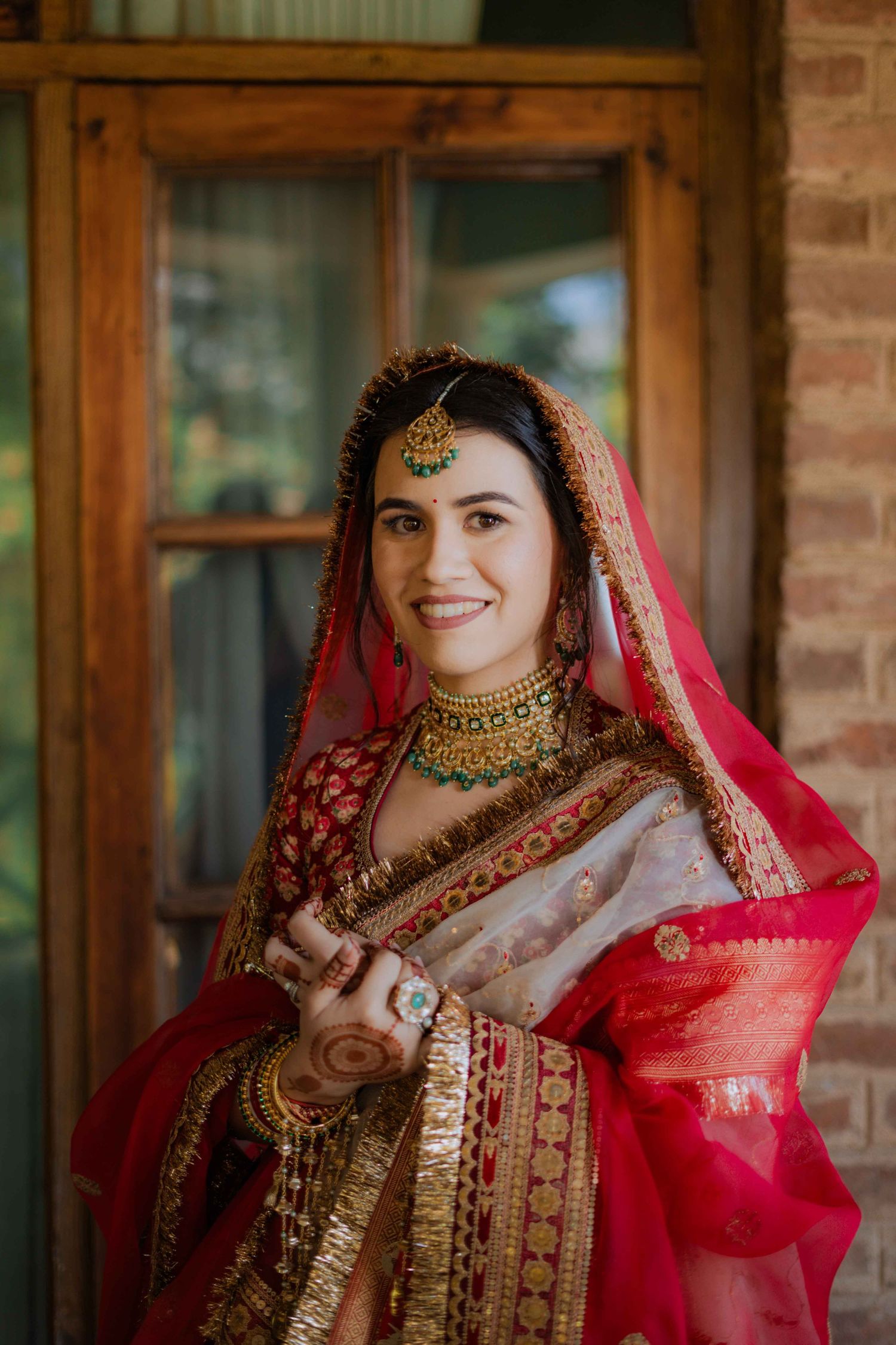 Traditional Indian bridal attire featuring an ornate red and gold lehenga with detailed embroidery and jewelry.