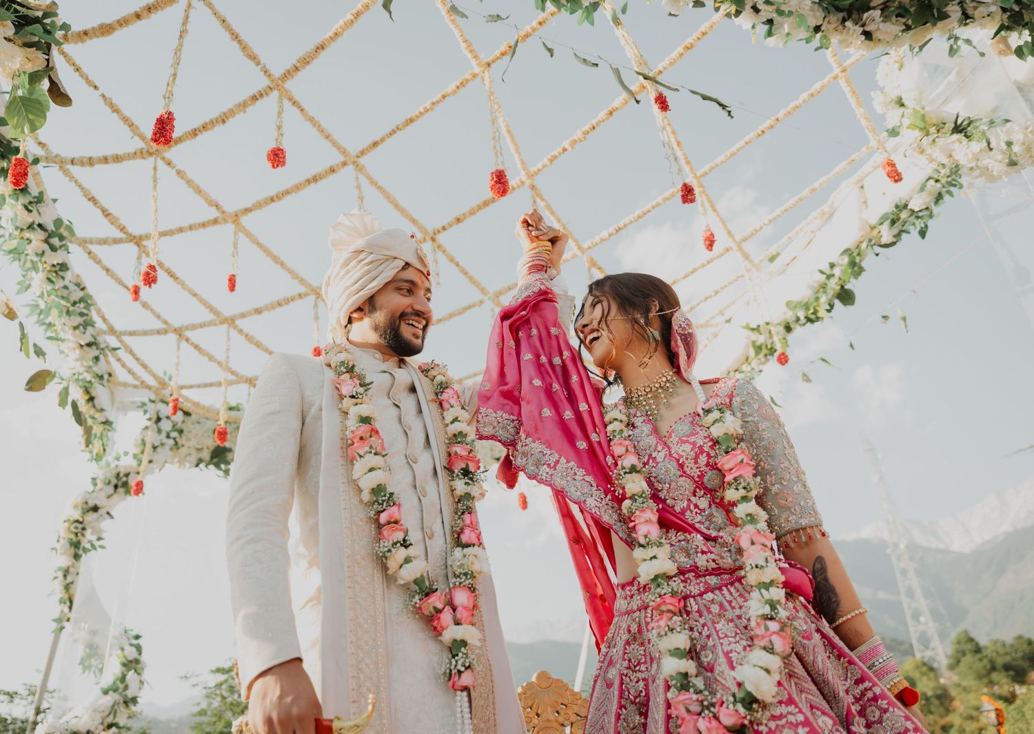 Outdoor wedding ceremony with floral arch decorations and traditional Indian wedding attire.