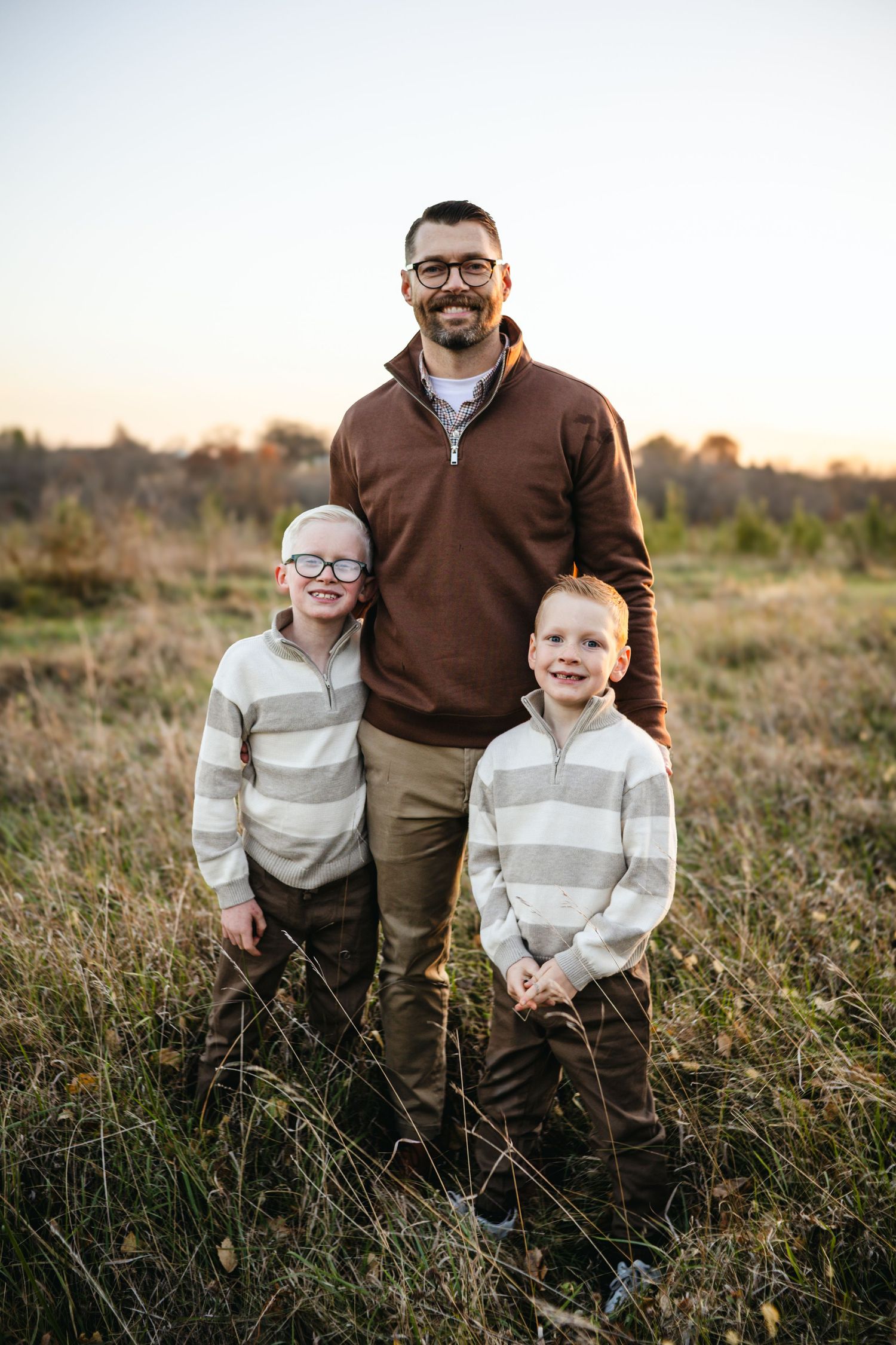 Three candid outdoor family photos taken in a grassy field at sunset with warm lighting and natural poses.