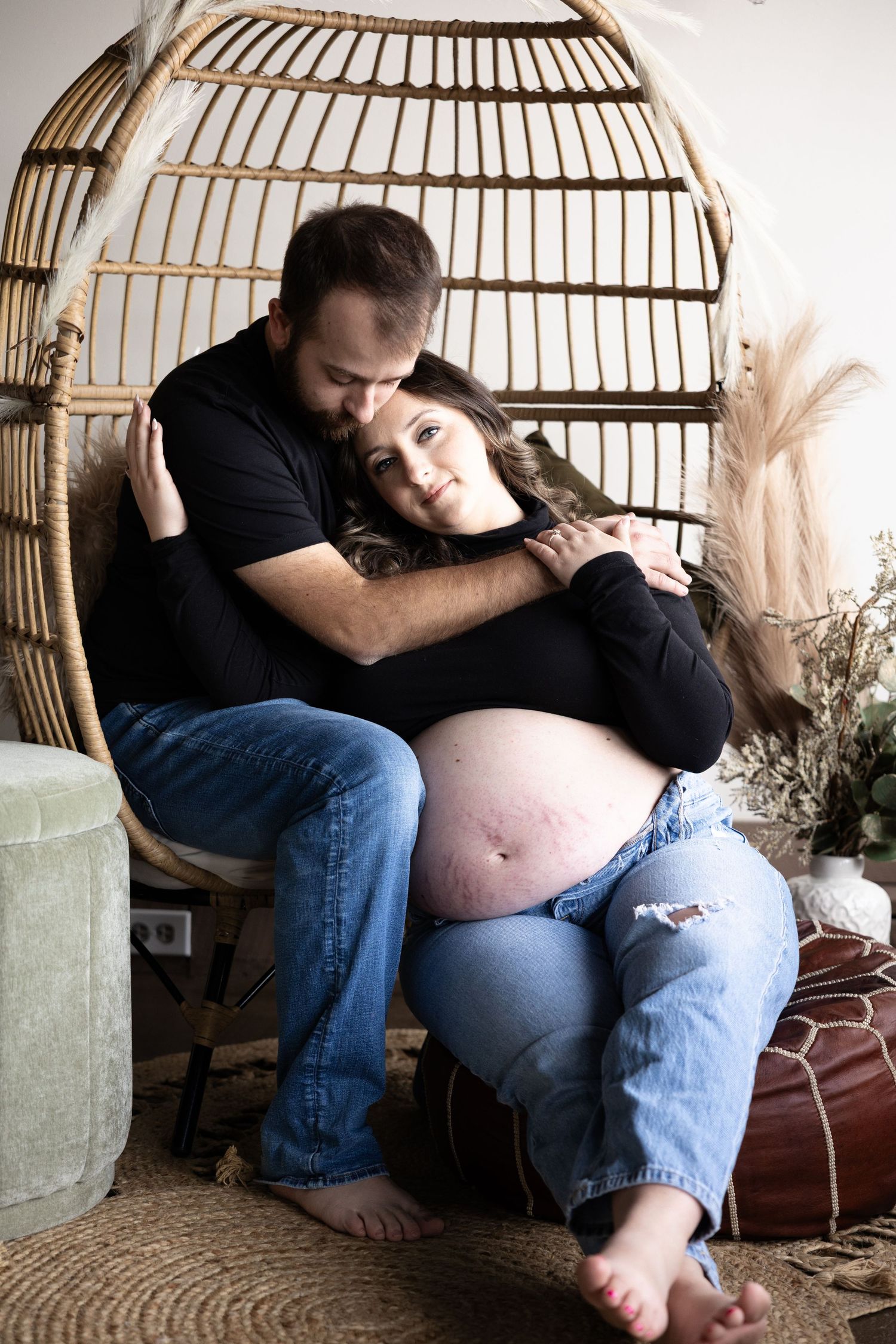 Intimate maternity photo series showing a pregnant person resting in a wicker hanging chair.