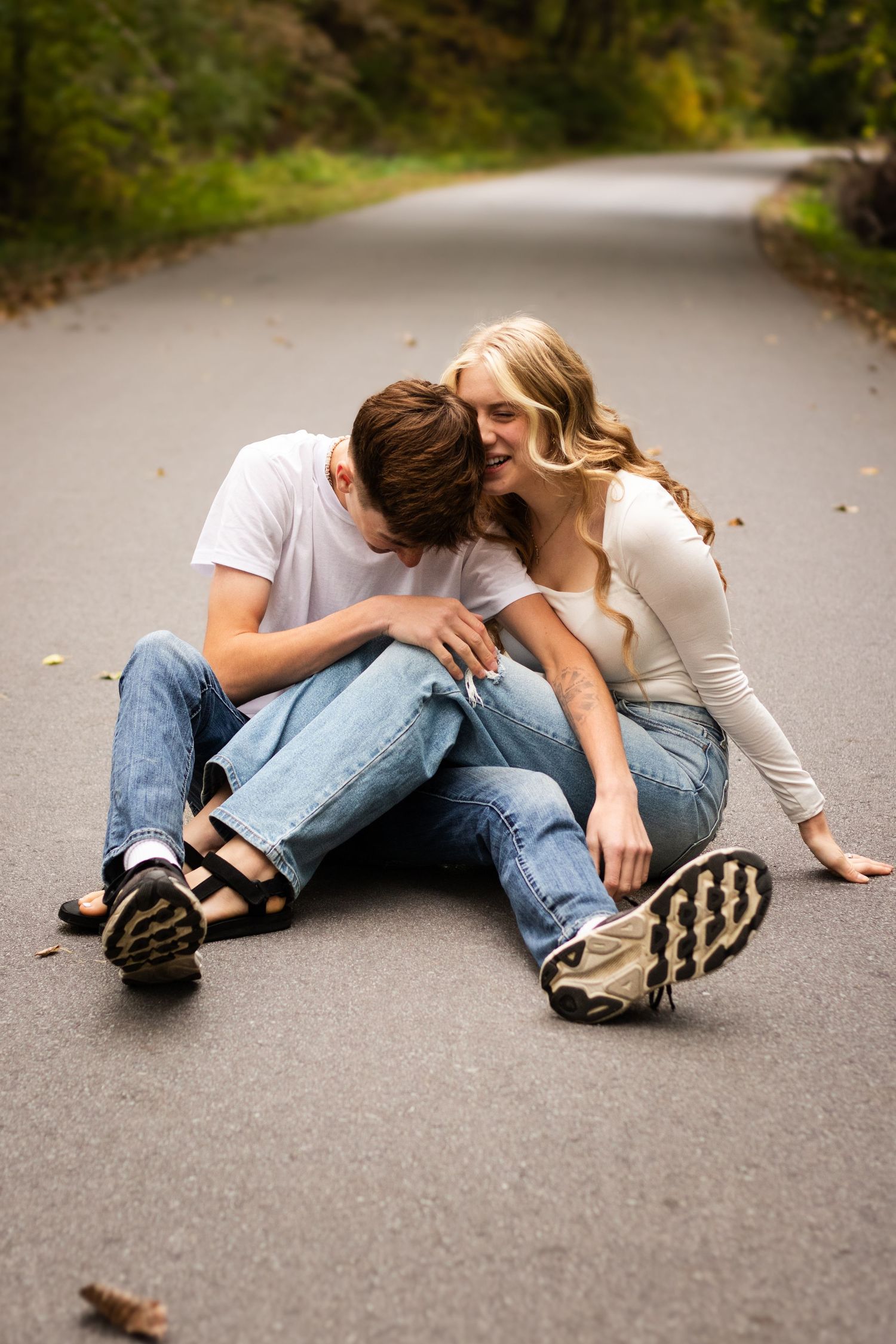 A romantic couple lying on a paved path outdoors shown in a creative sequence of poses.