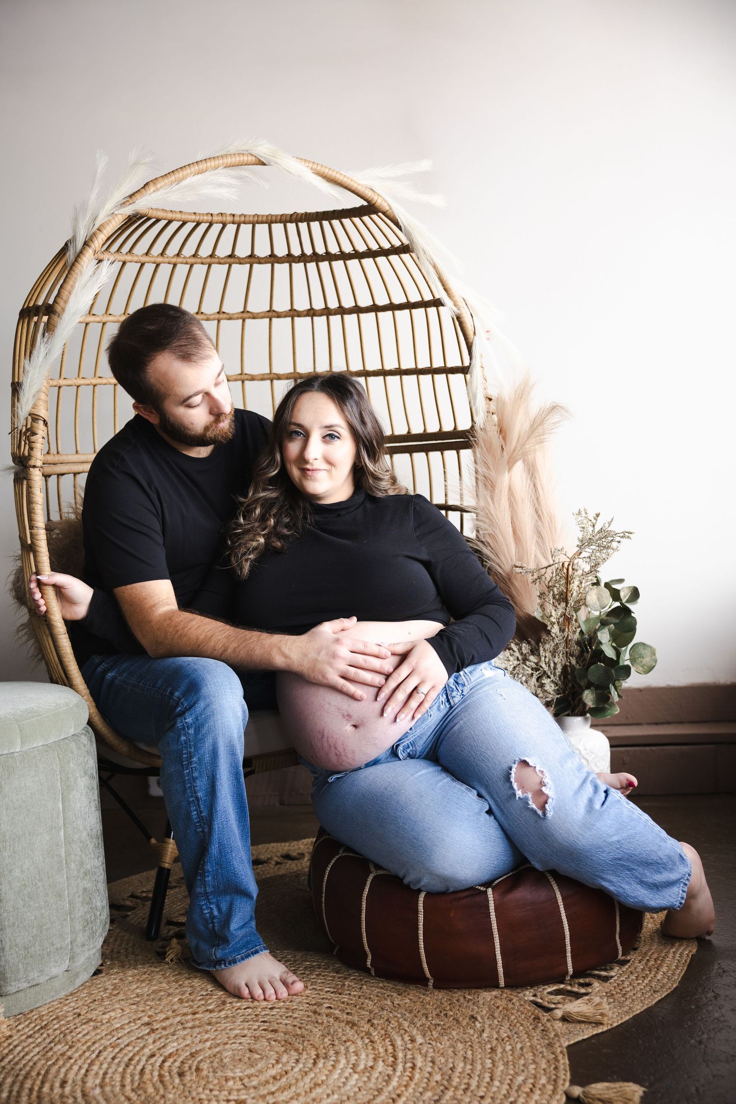 Intimate maternity photos captured in a rattan egg chair with natural decor elements.