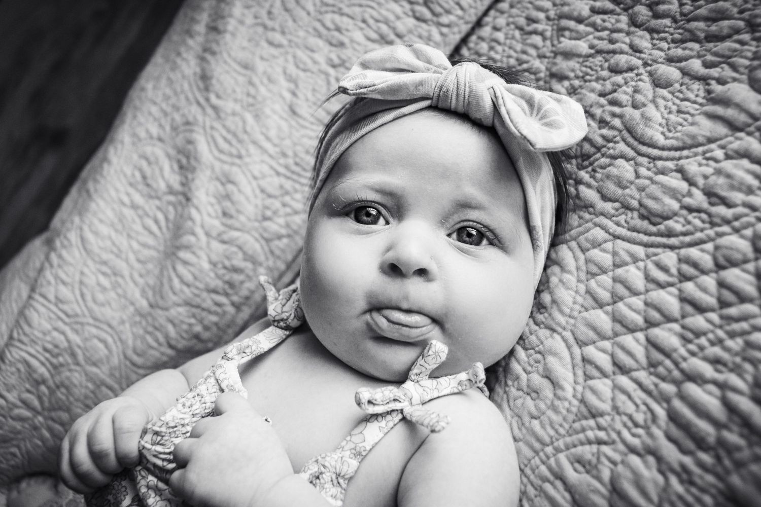 Black and white photo collection of an infant making different faces on a textured blanket.