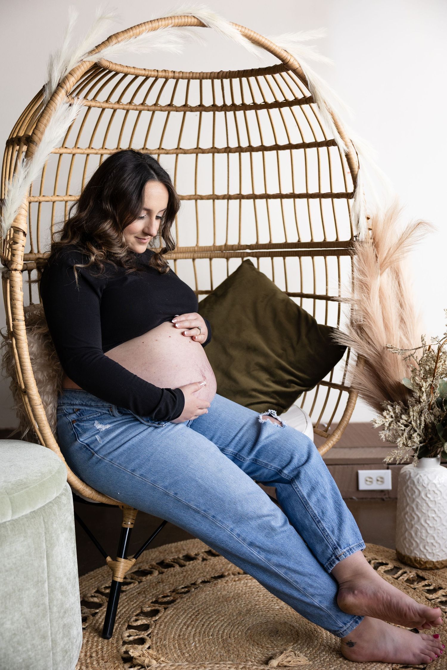 A couple relaxes together in a cozy rattan hanging chair with decorative elements in the background.