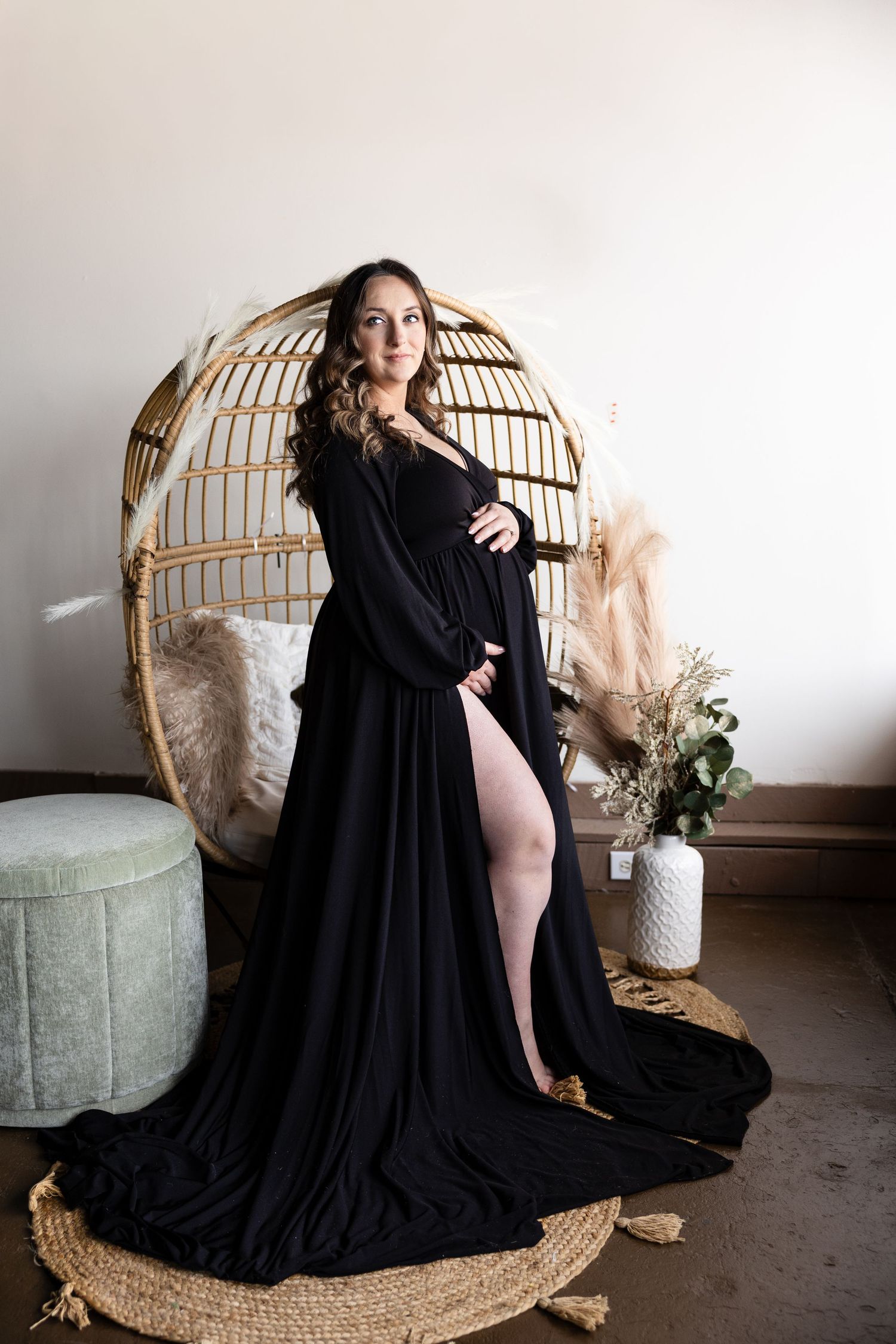 A black flowing dress elegantly draped across a rattan chair with soft neutral decor and dried pampas grass.