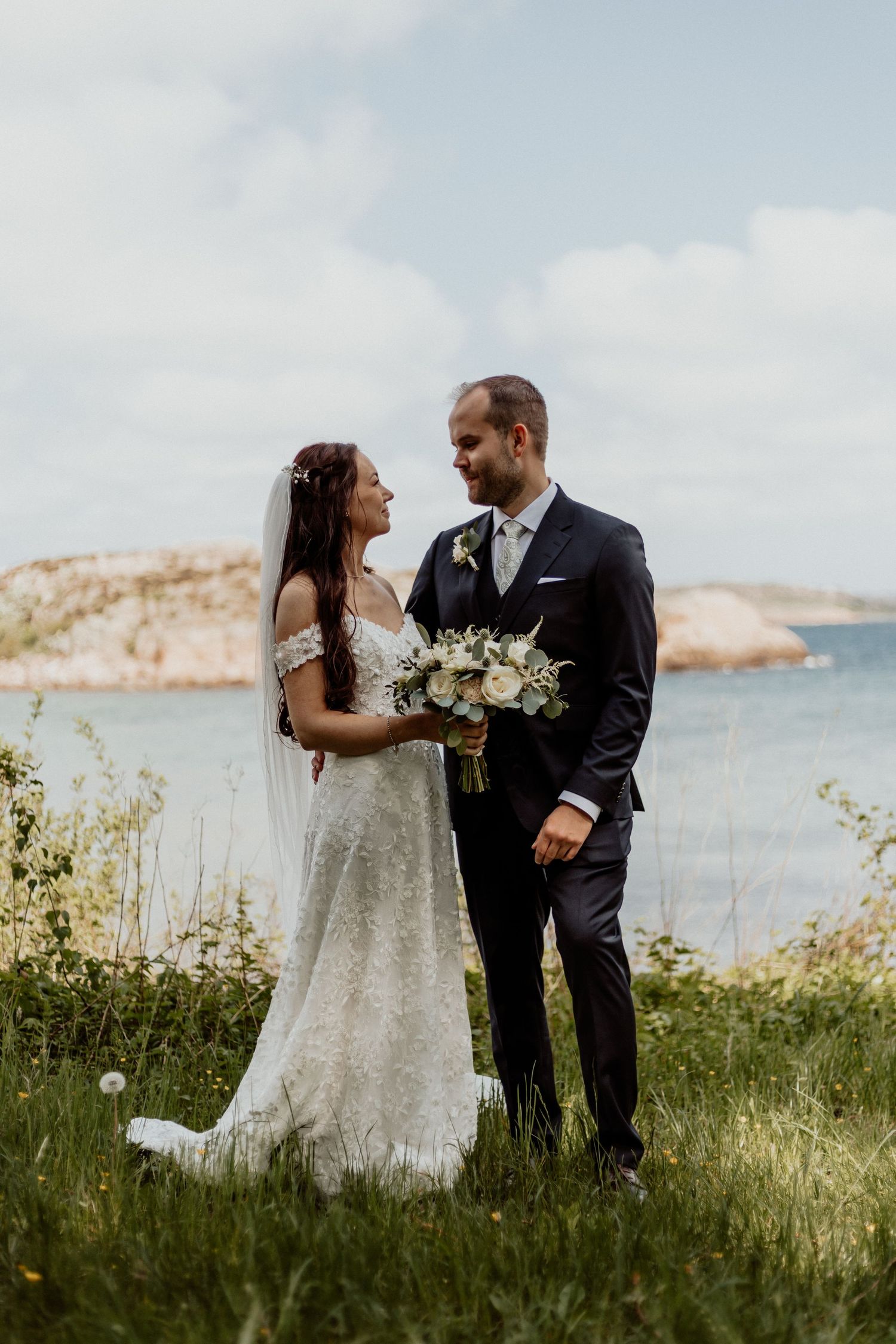 porträtt av brudpar på en gräsmatta med hav och klippor i bakgrunden på vackra bohus malmön