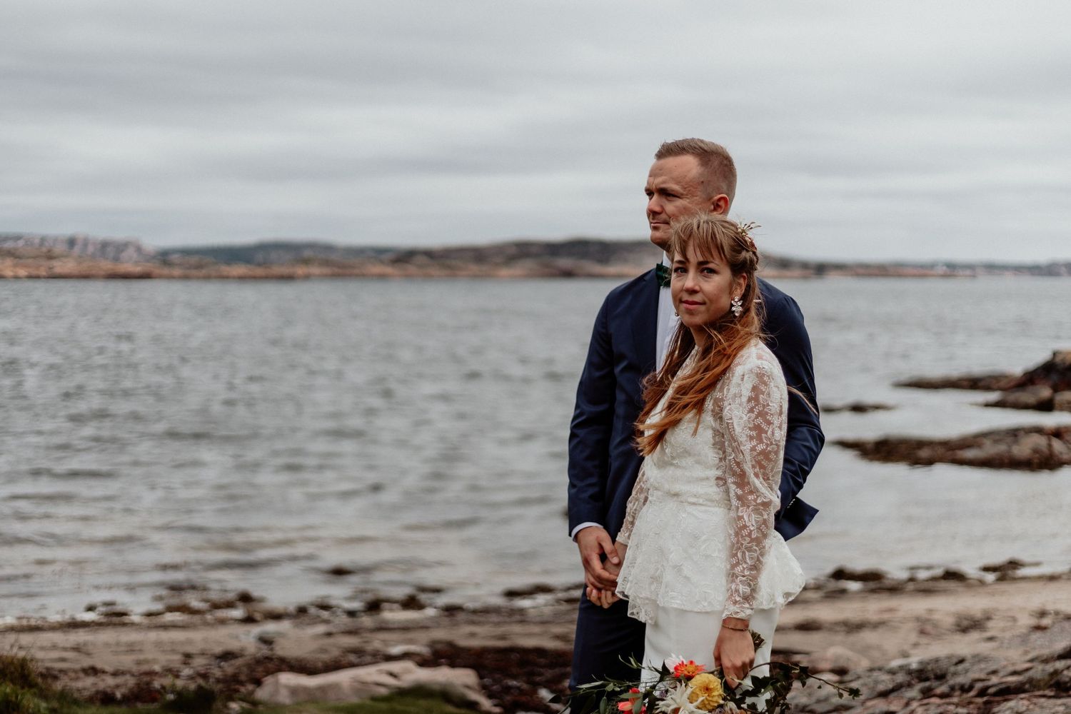 Vackert porträtt av bröllopsbar på en strand på Bohus-malmön precis vid havet och klippor.