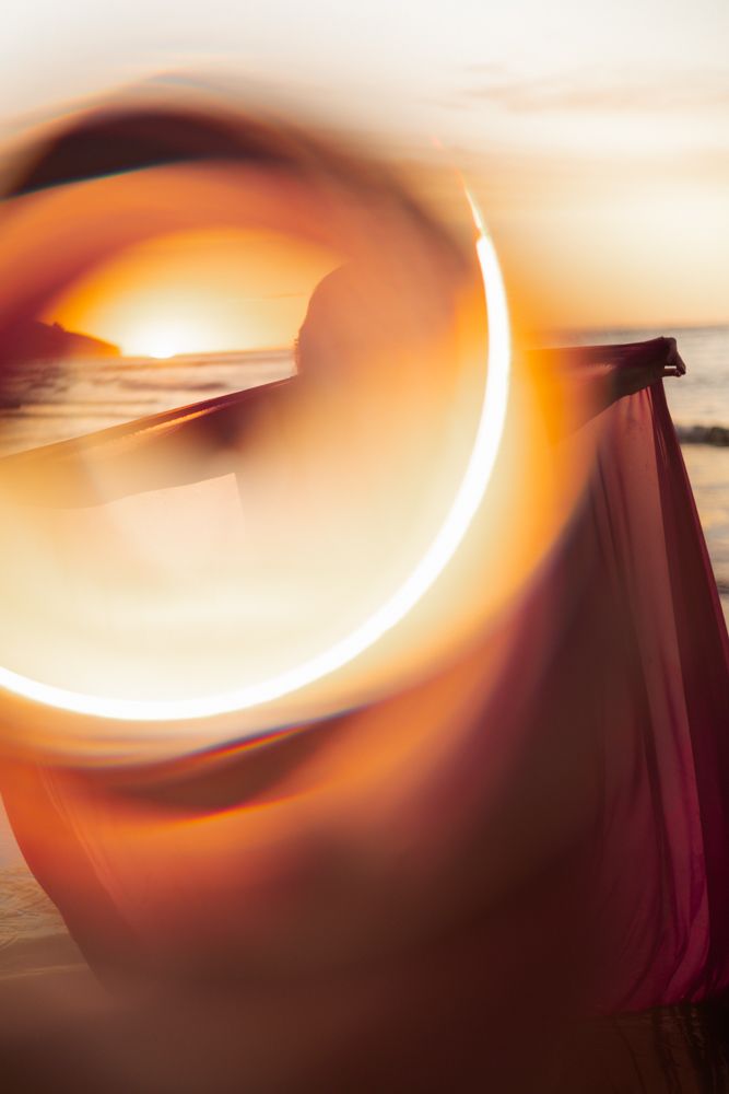 Woman in red on the beach using a halo filter that creates a mystical circle effect.