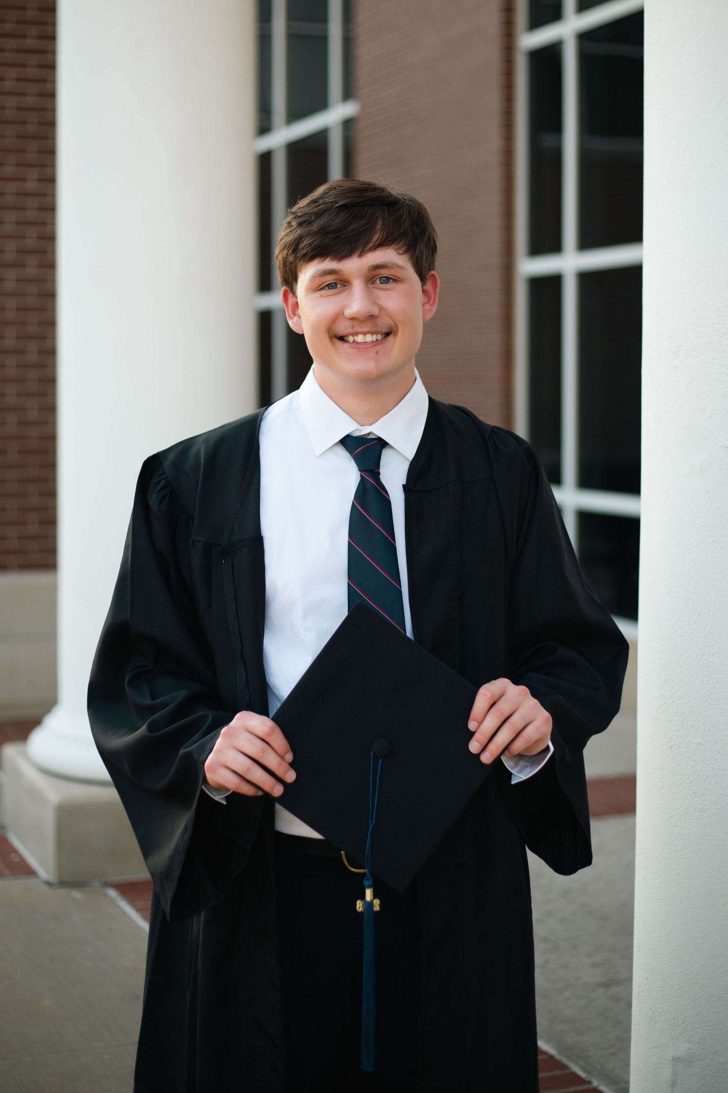 Portrait of a young man in cap and gown for college graduation