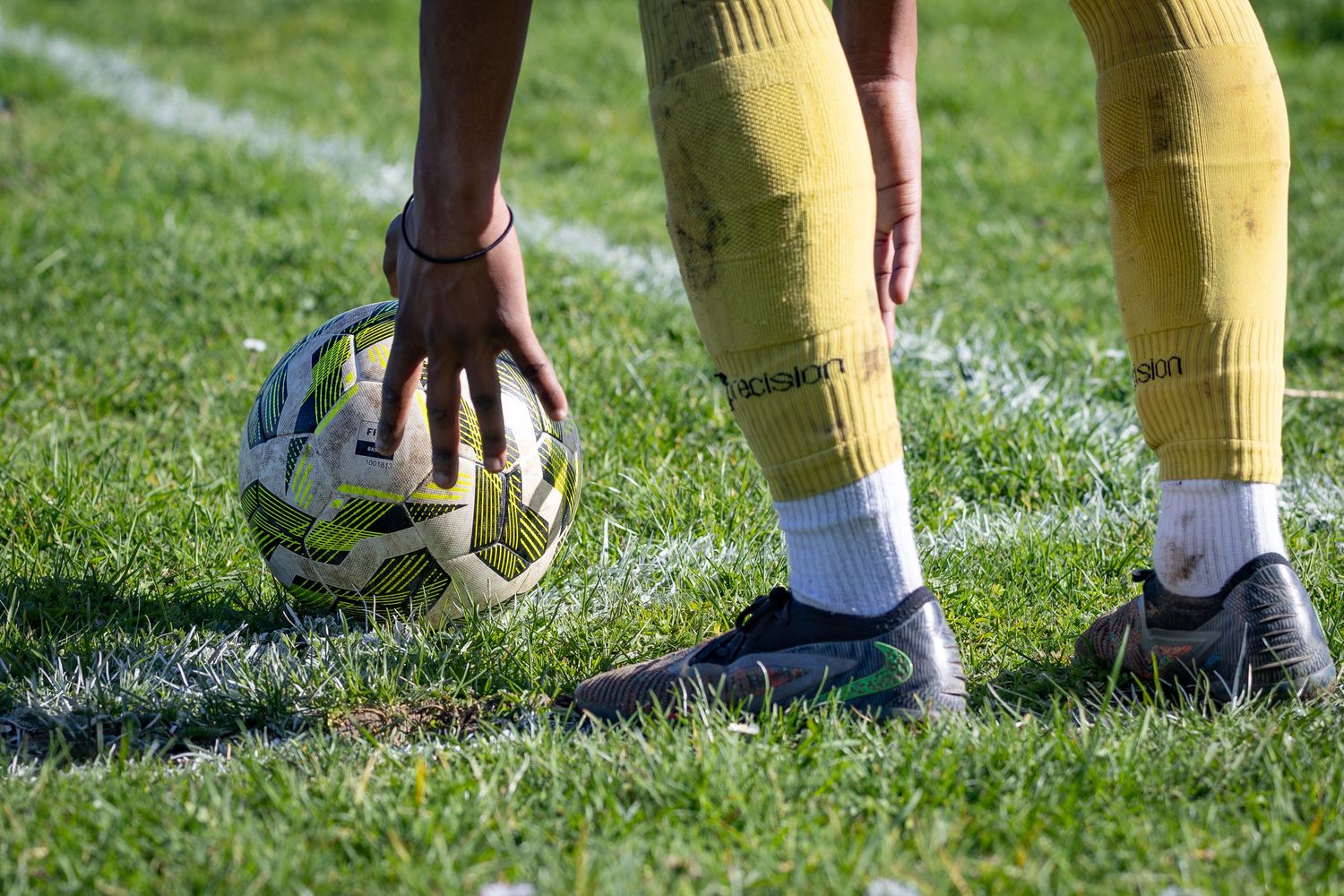player reaching down to adjust ball to take a corner, football