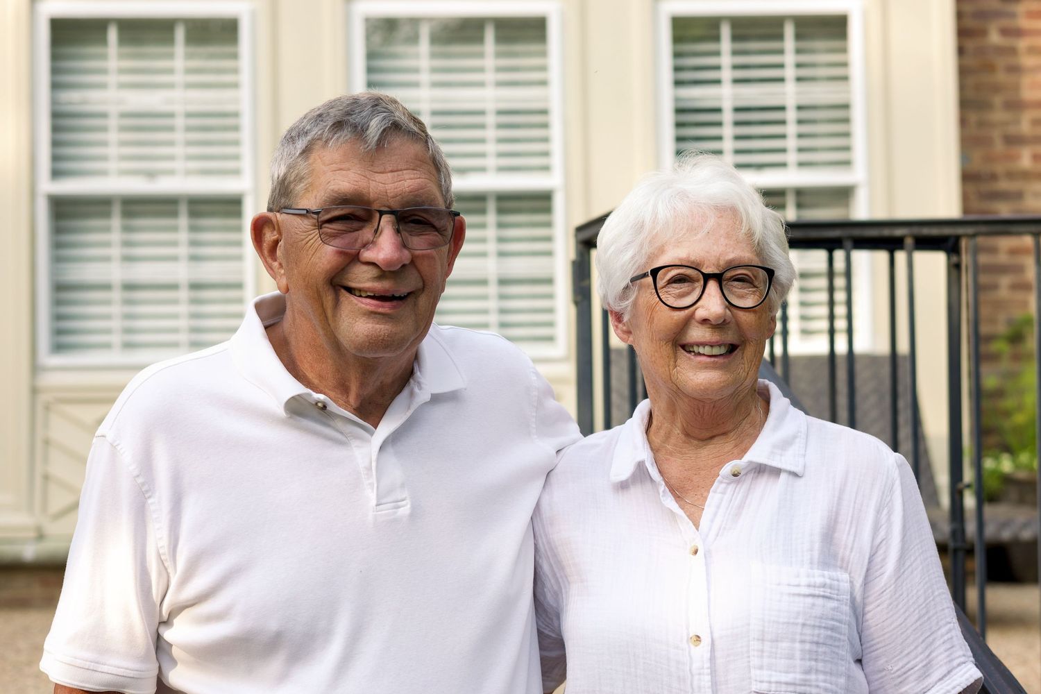 Smiling senior couple posing outdoors in front of a building.