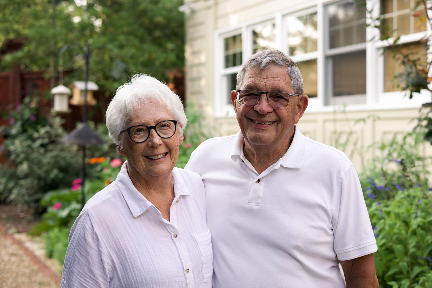 Happy senior couple standing together in a lush garden setting.