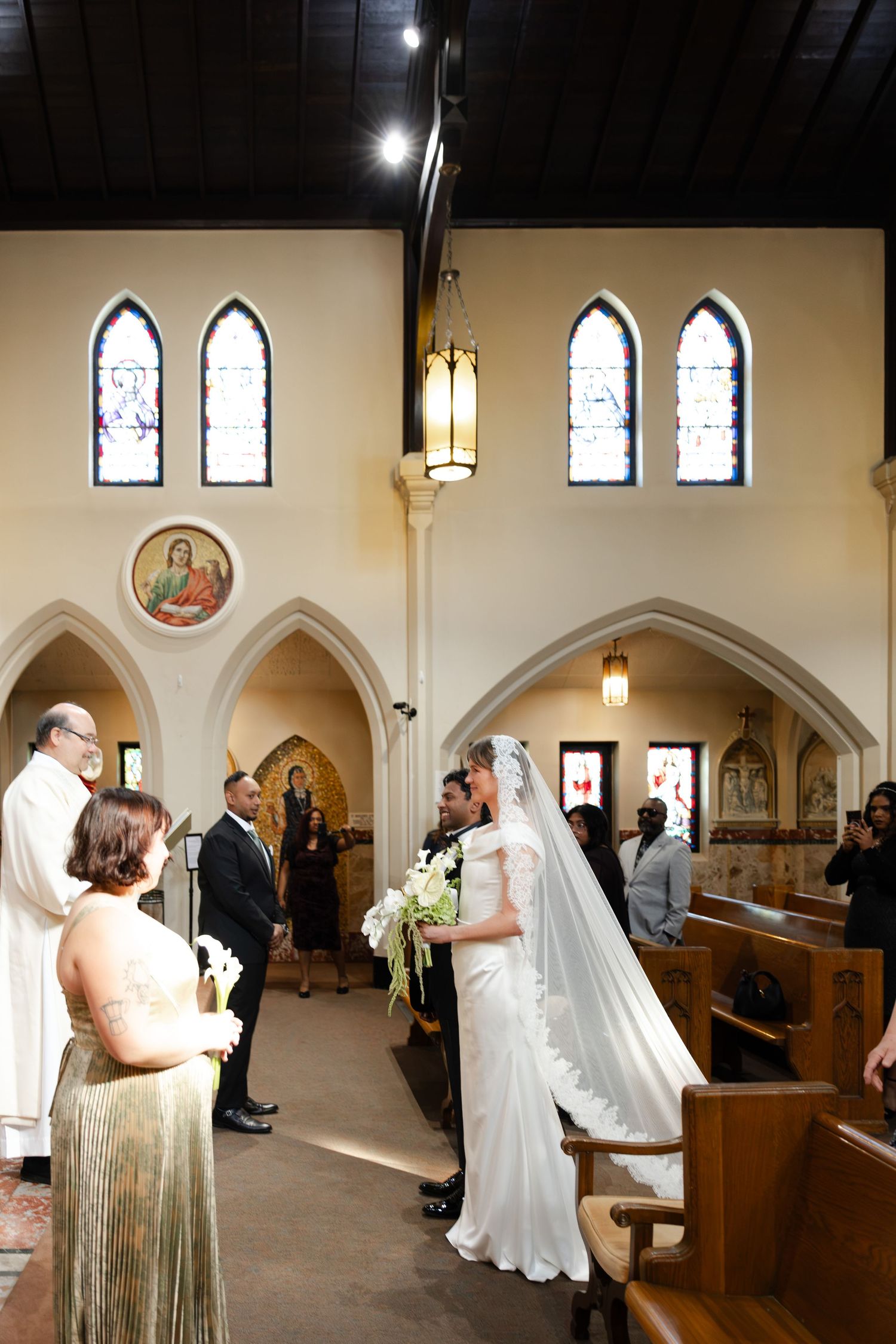 Bride walking down the aisle in a white gown and veil during a church wedding ceremony.
