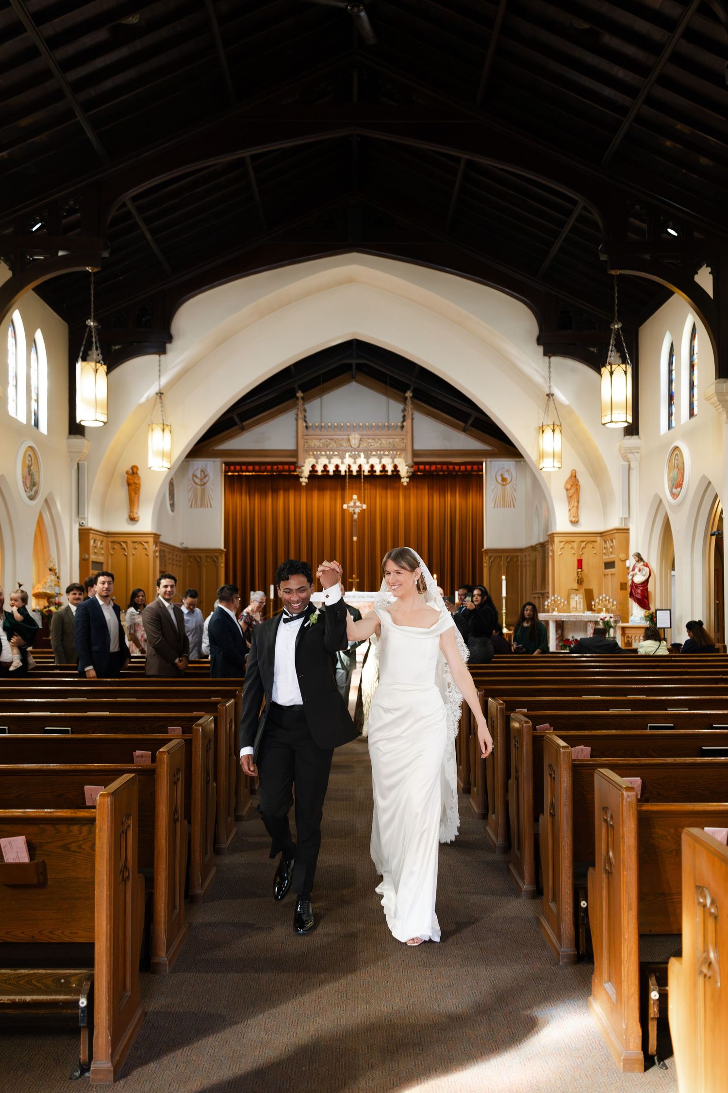 Newlyweds walk down the aisle of a traditional church after their wedding ceremony.