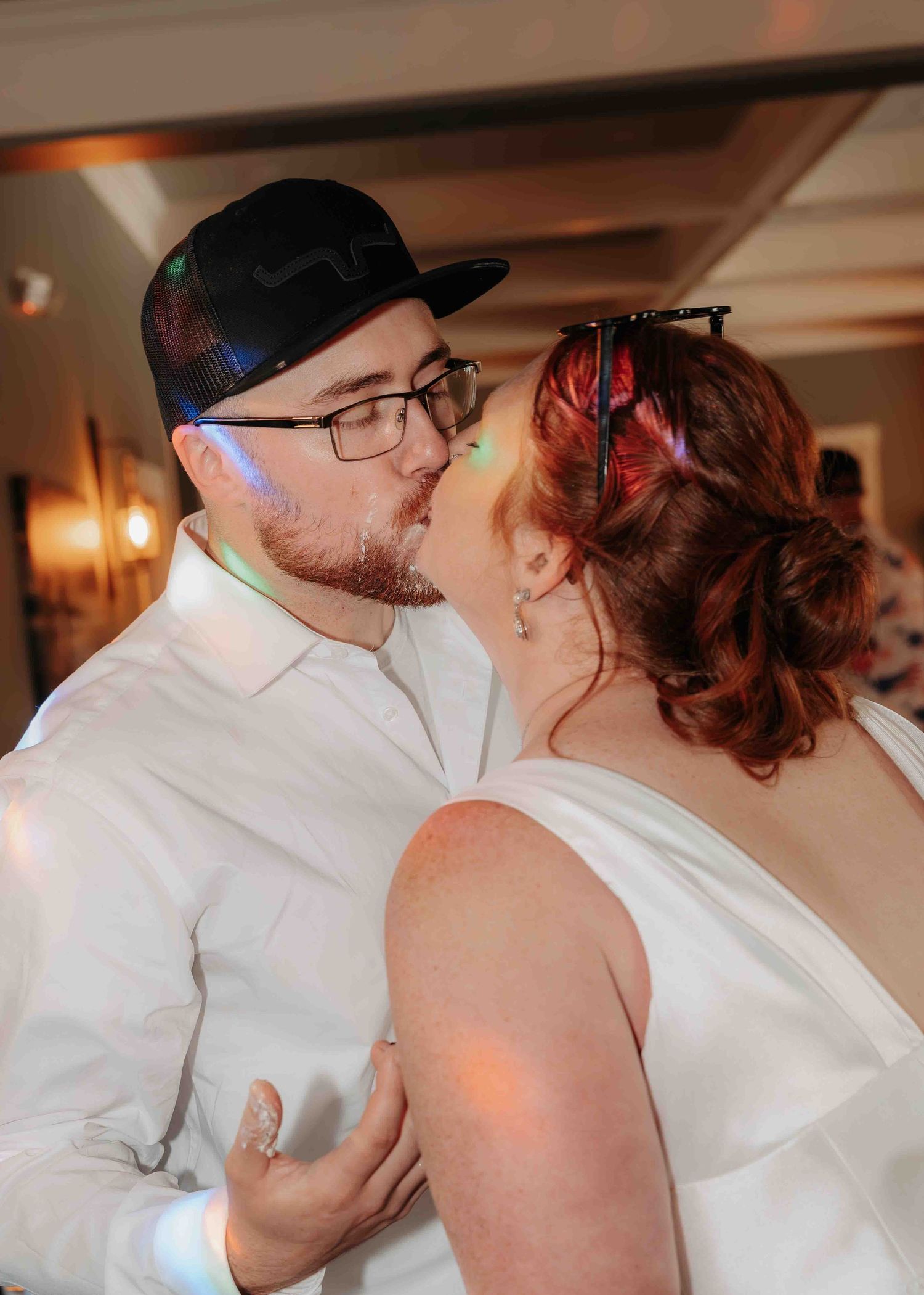 Bride and groom share a romantic kiss on the dance floor during their wedding reception.