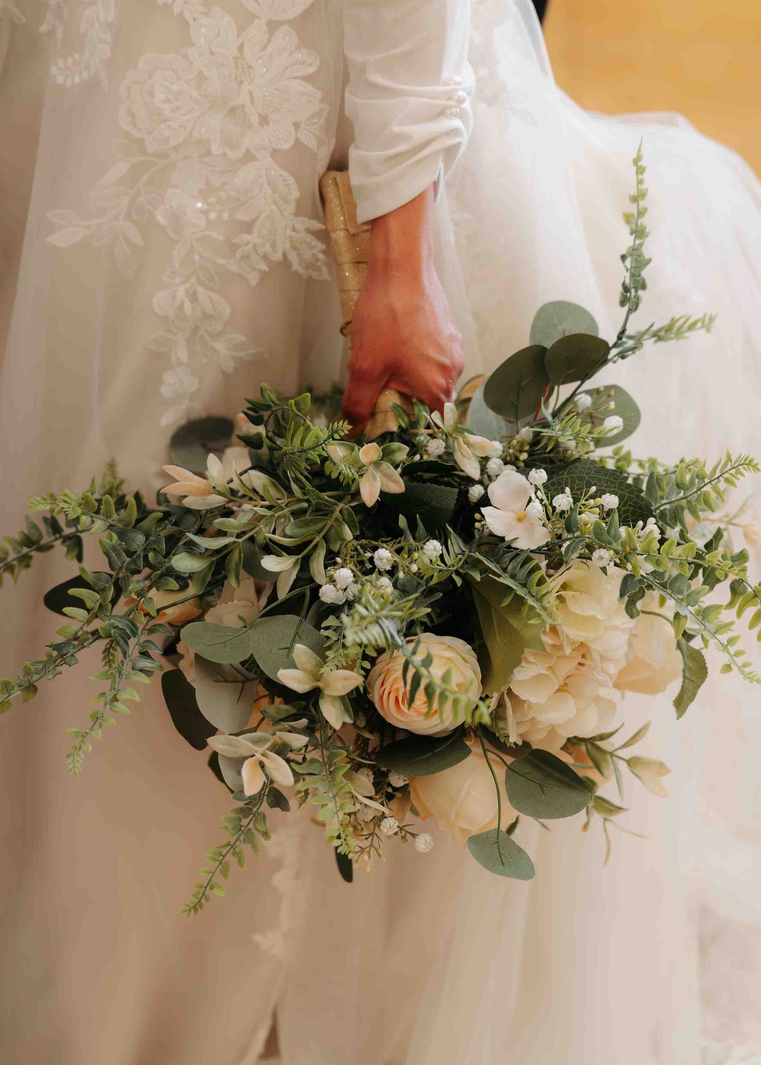 Bride holds a lush bridal bouquet of white peonies and eucalyptus greenery.