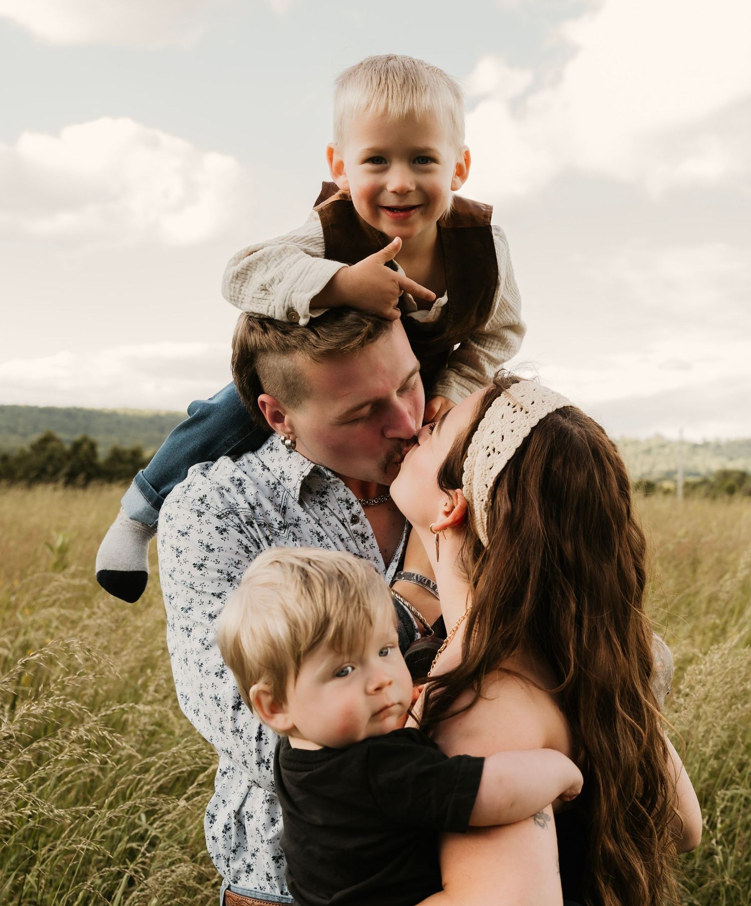 Happy family with two young boys sharing a tender moment together in a sunny meadow.