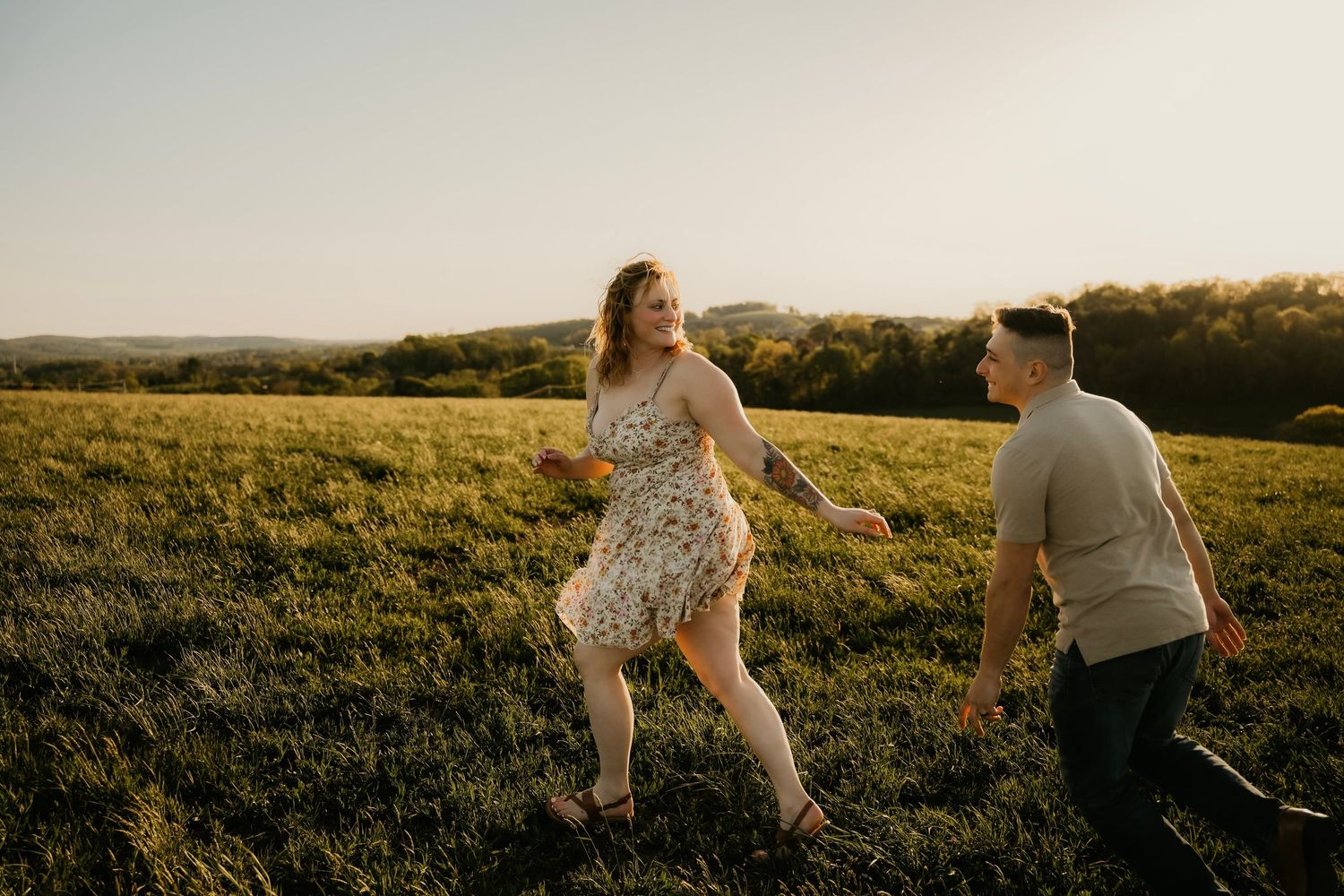 Couple playfully running through a golden sunlit meadow at sunset.
