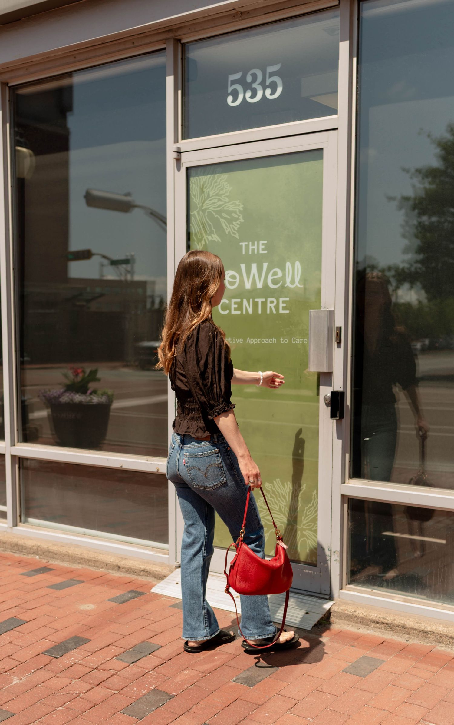 Woman in black top with red handbag entering The Howell Centre at 535.