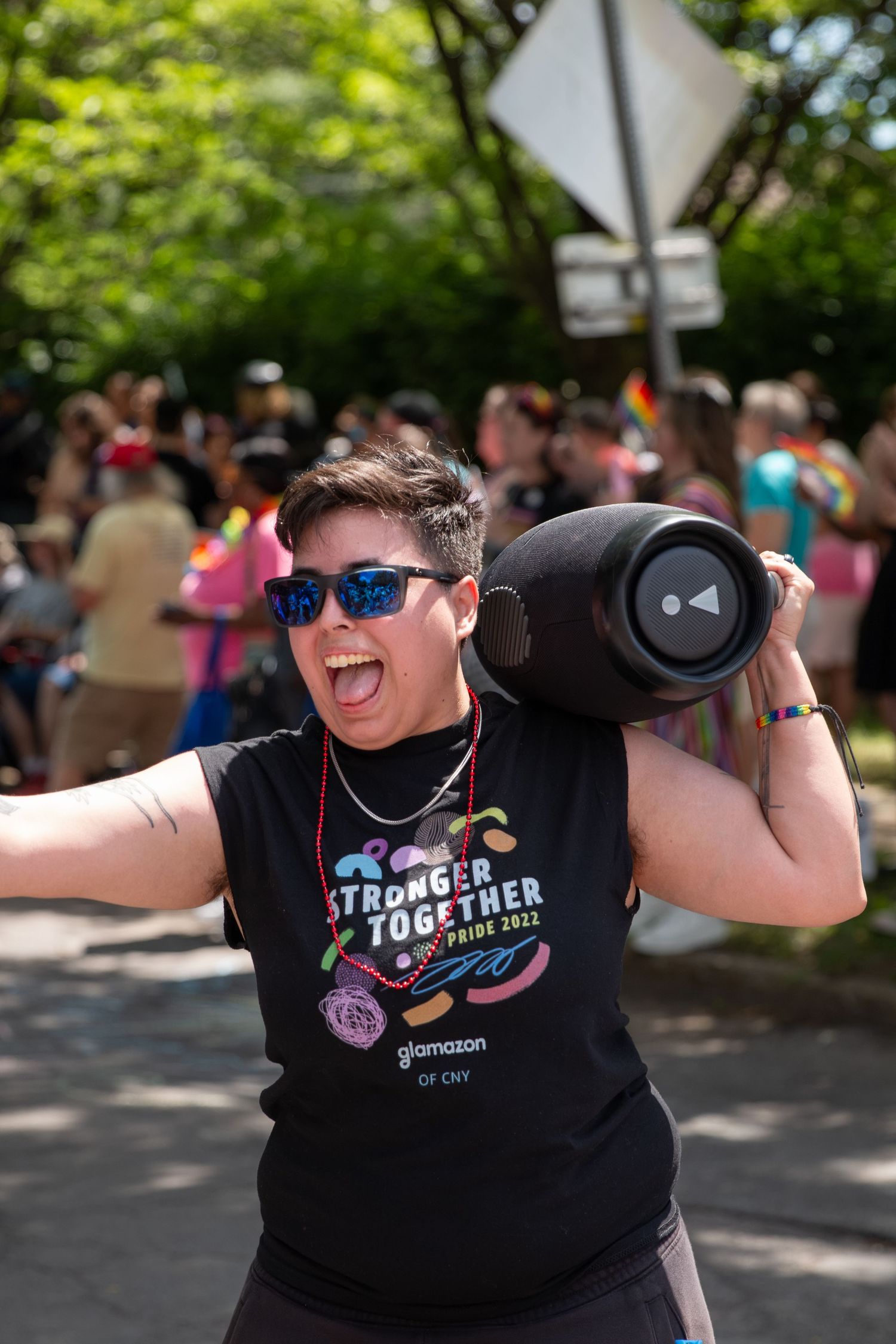 A person holding a speaker on their shoulder, happily screaming while holding their arm out to hug someone.