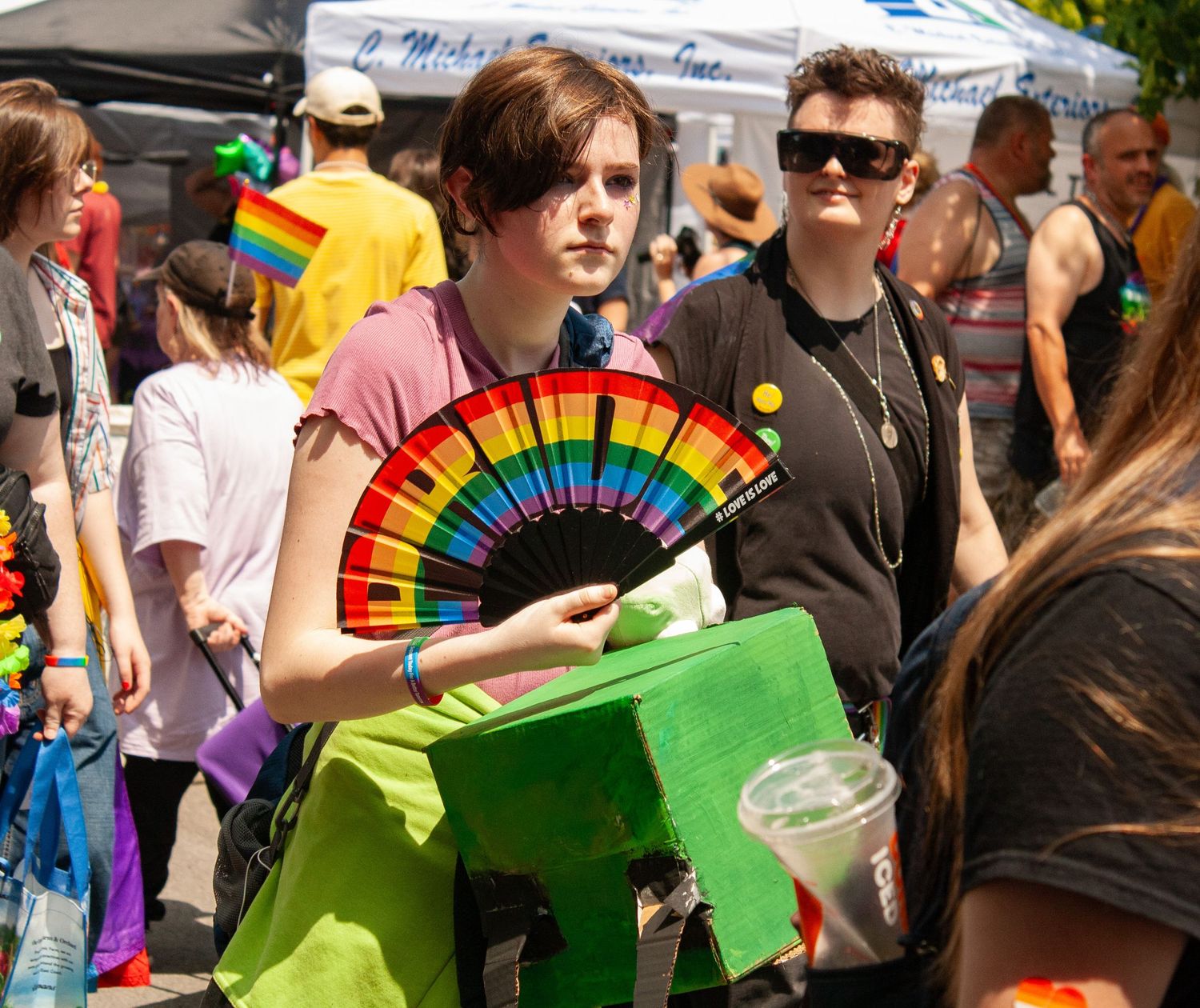 A person looking off into the distance while holding a fan that says 