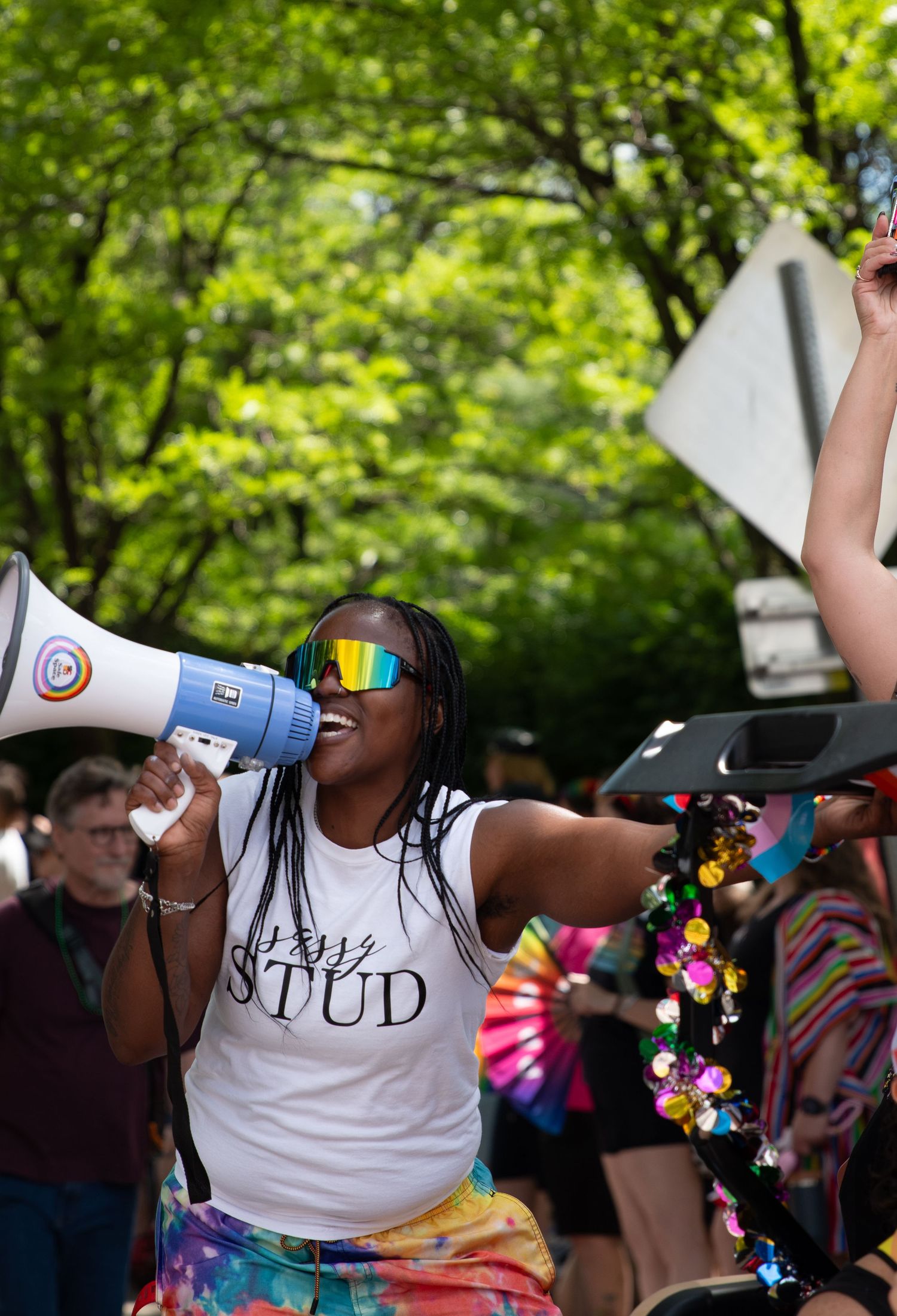 A person smiling while yelling into a megaphone while hanging off a golf cart.