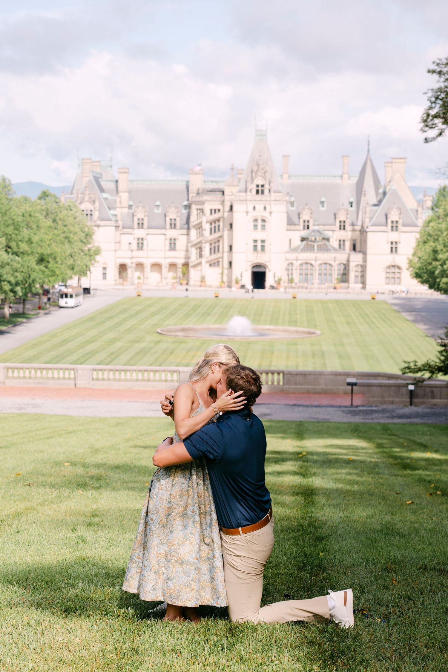 Couple embracing during a romantic proposal on the lawn of the Biltmore Estate in Asheville, NC.