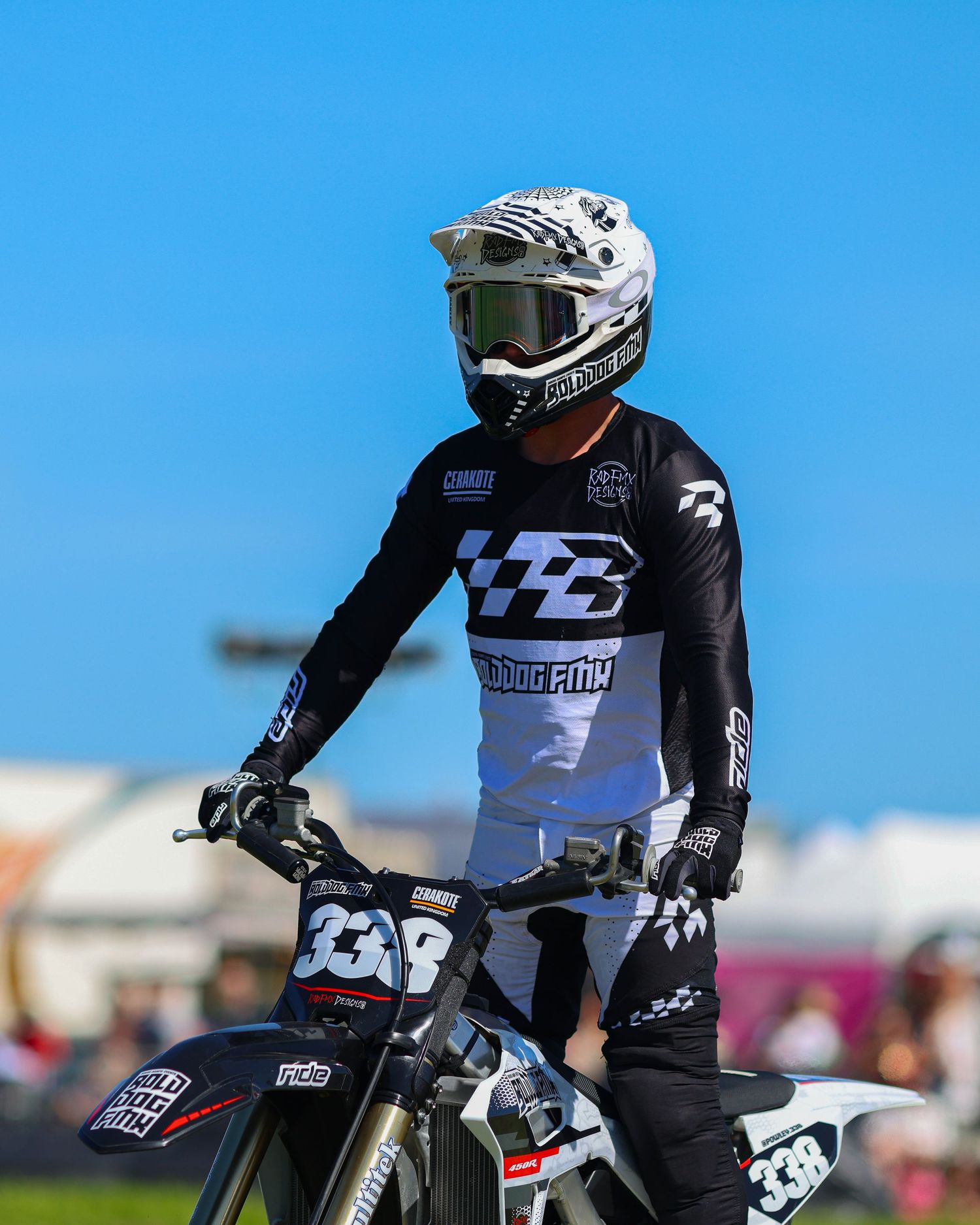 Motocross rider in black and white gear sits on bike number 338 under a bright blue sky. Photo Taken by AJCoatesPhotography