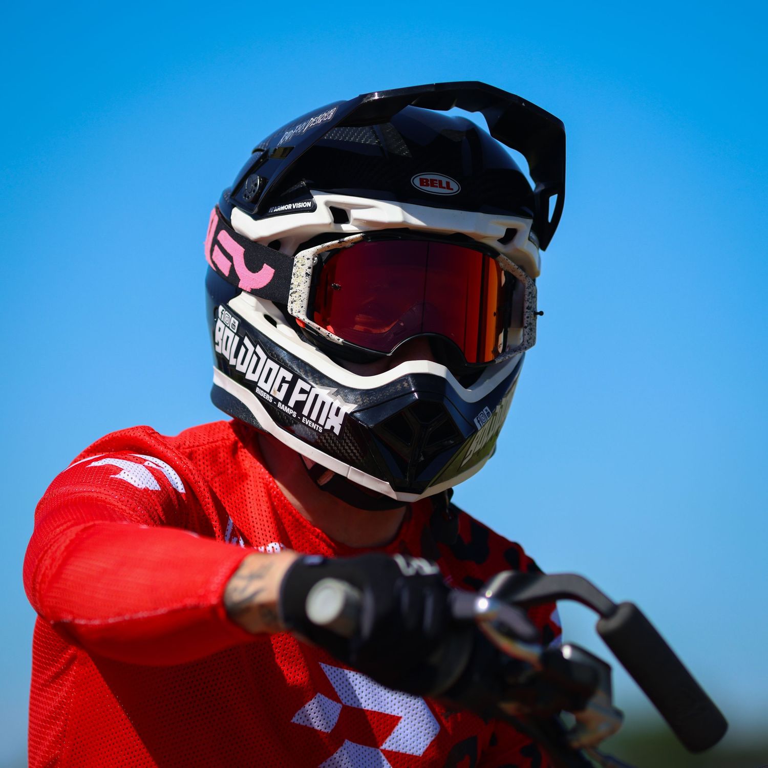 Close-up portrait of a motocross rider wearing a Bell helmet with Bulldog FMX branding and red goggles. Photo Taken by AJCoatesPhotography