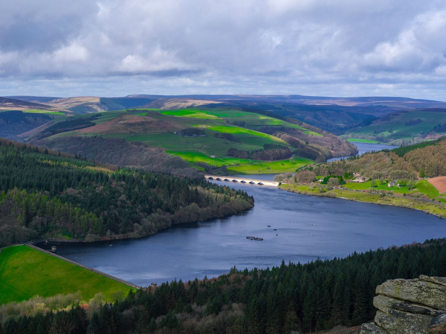 Aerial view of Ladybower Reservoir surrounded by green hills and forests under a cloudy sky in Derbyshire, England. Photo Taken by AJCoatesP