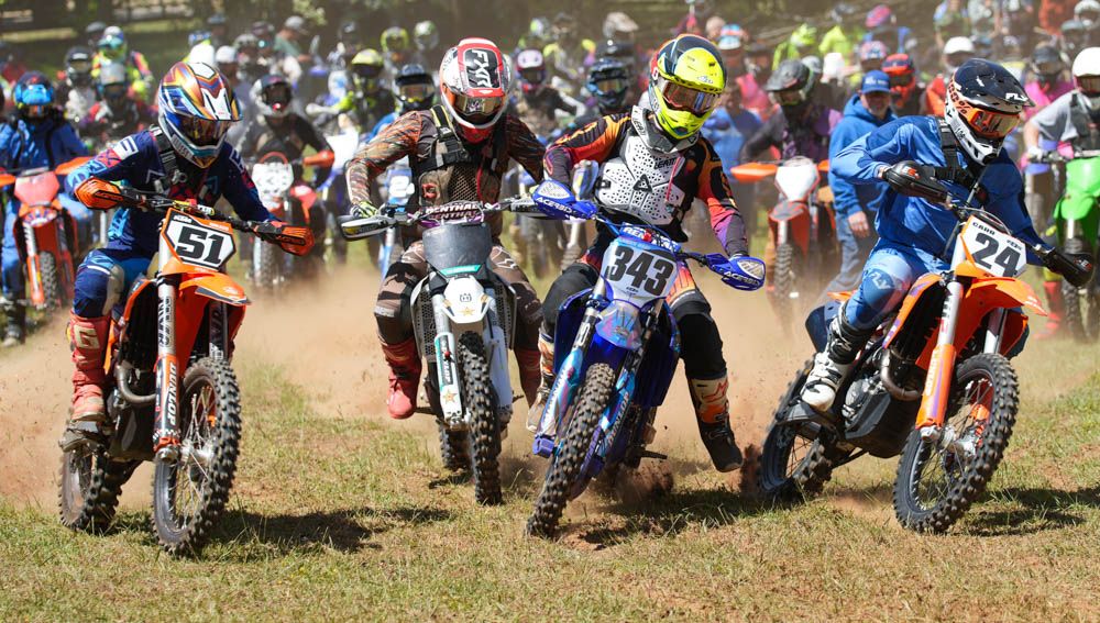 Group of motocross riders lined up at the start of a race.