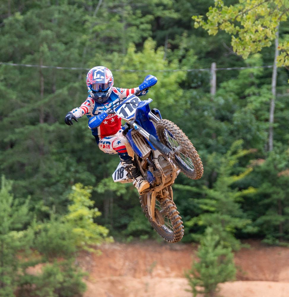 Motocross rider performing a whip while airborne over a jump.
