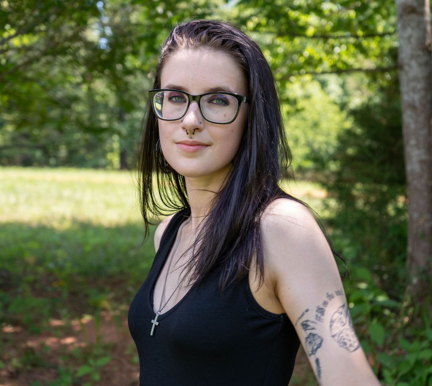 Outdoor portrait of a woman with dark hair and glasses.