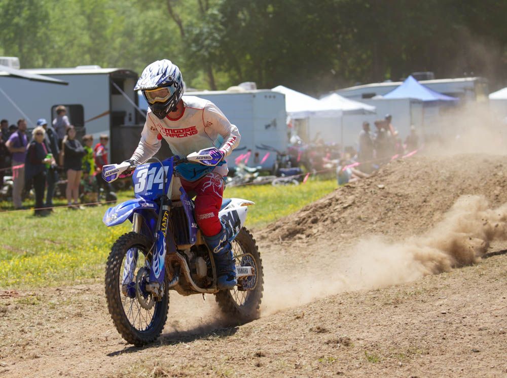 Motocross rider racing toward the camera through a dusty section of track.