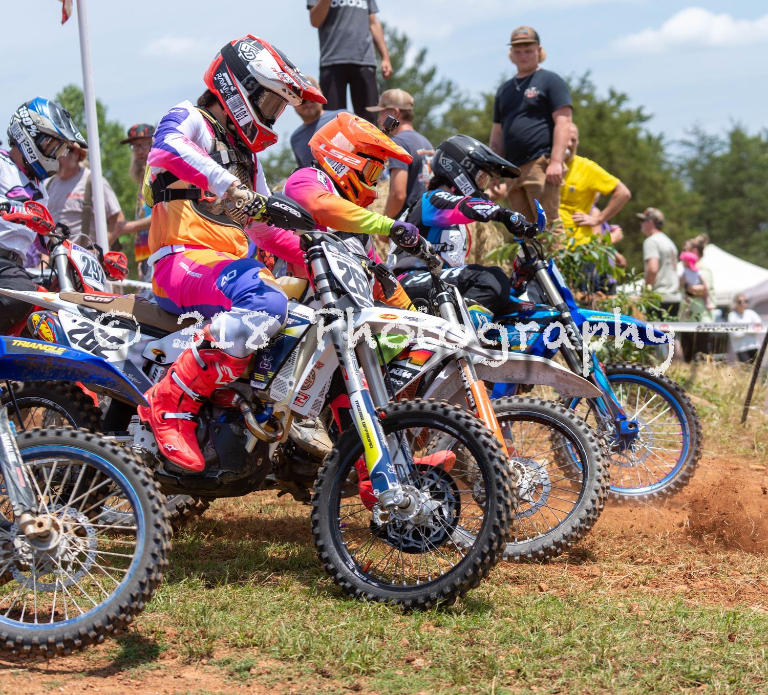 Motocross riders lined up together at the start of a race.