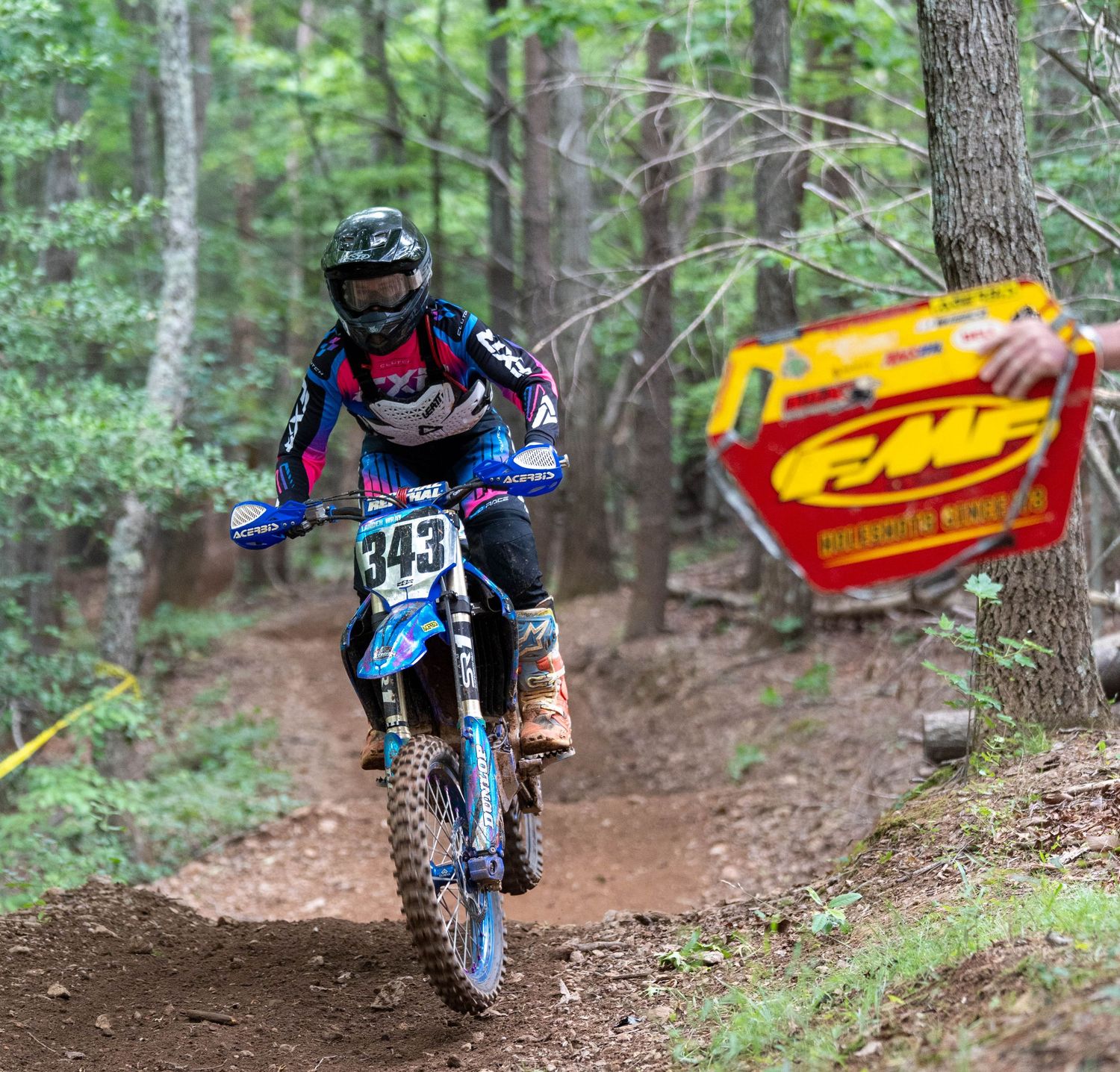 Hare scramble rider racing along a wooded trail.