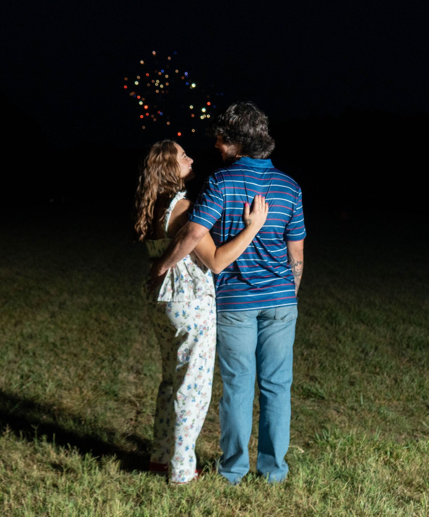 Couple embracing outdoors beneath fireworks at night