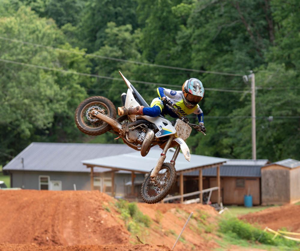Motocross rider performing a sideways whip over a dirt jump.