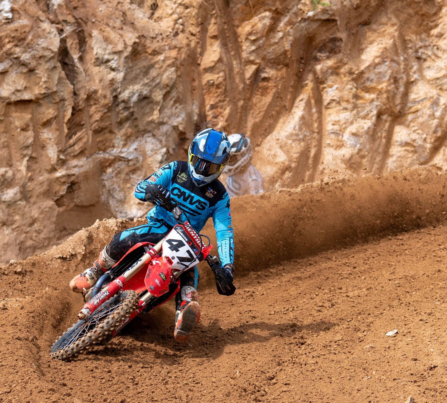 Motocross rider carving through a steep dirt berm.